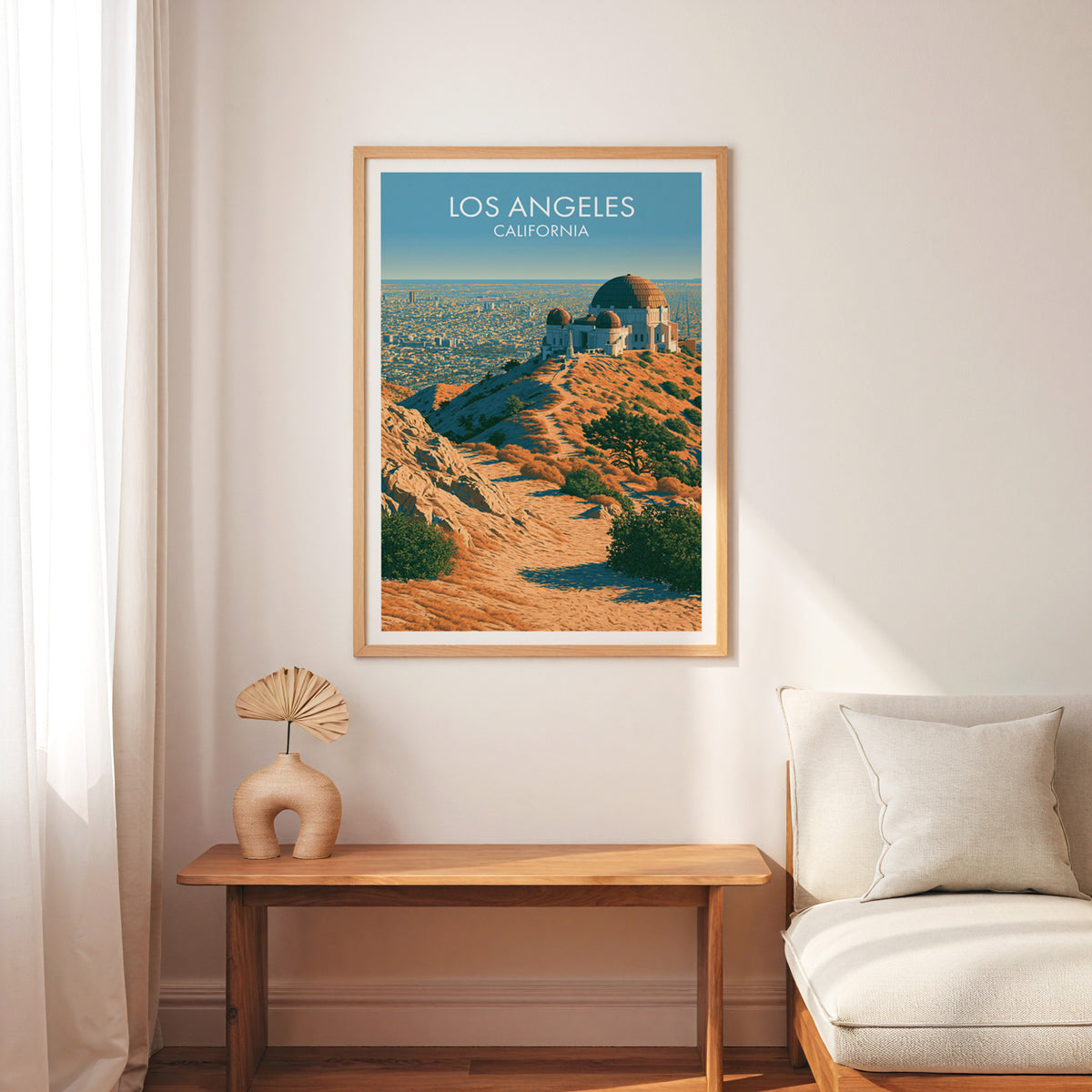 Griffith Observatory travel print in an oak frame over a slim bench beside a cream armchair.