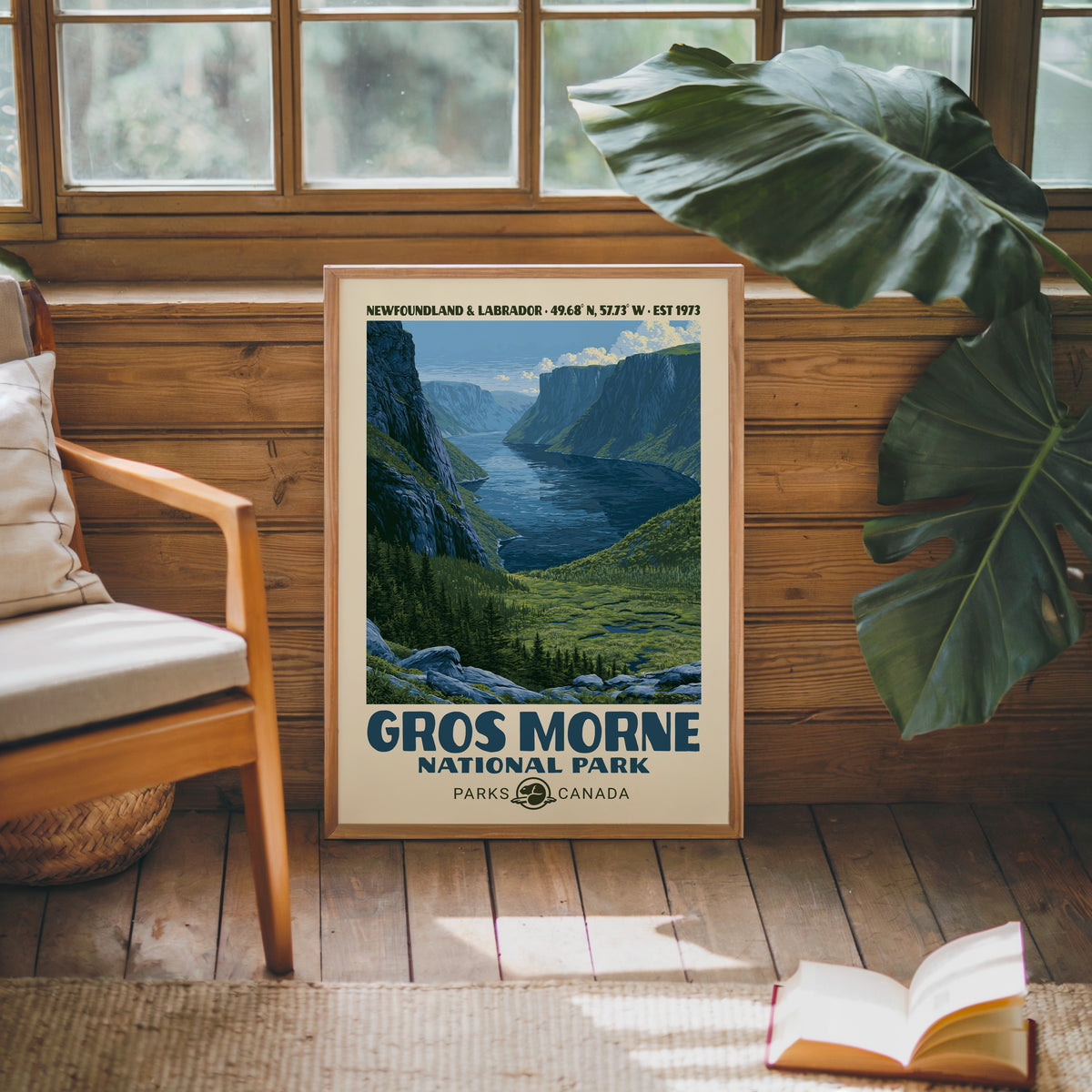 Gros Morne Canada vintage poster in an oak frame against a pine cabin wall beside a monstera