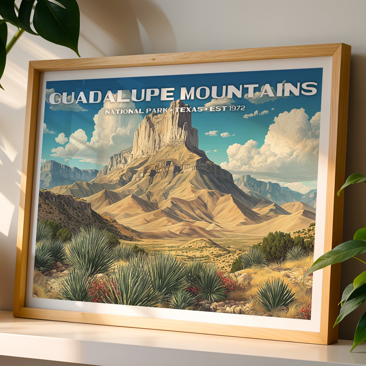 Guadalupe Mountains National Park wall art print in a light oak frame, leaning on a white shelf in warm sunlight beside a monstera plant