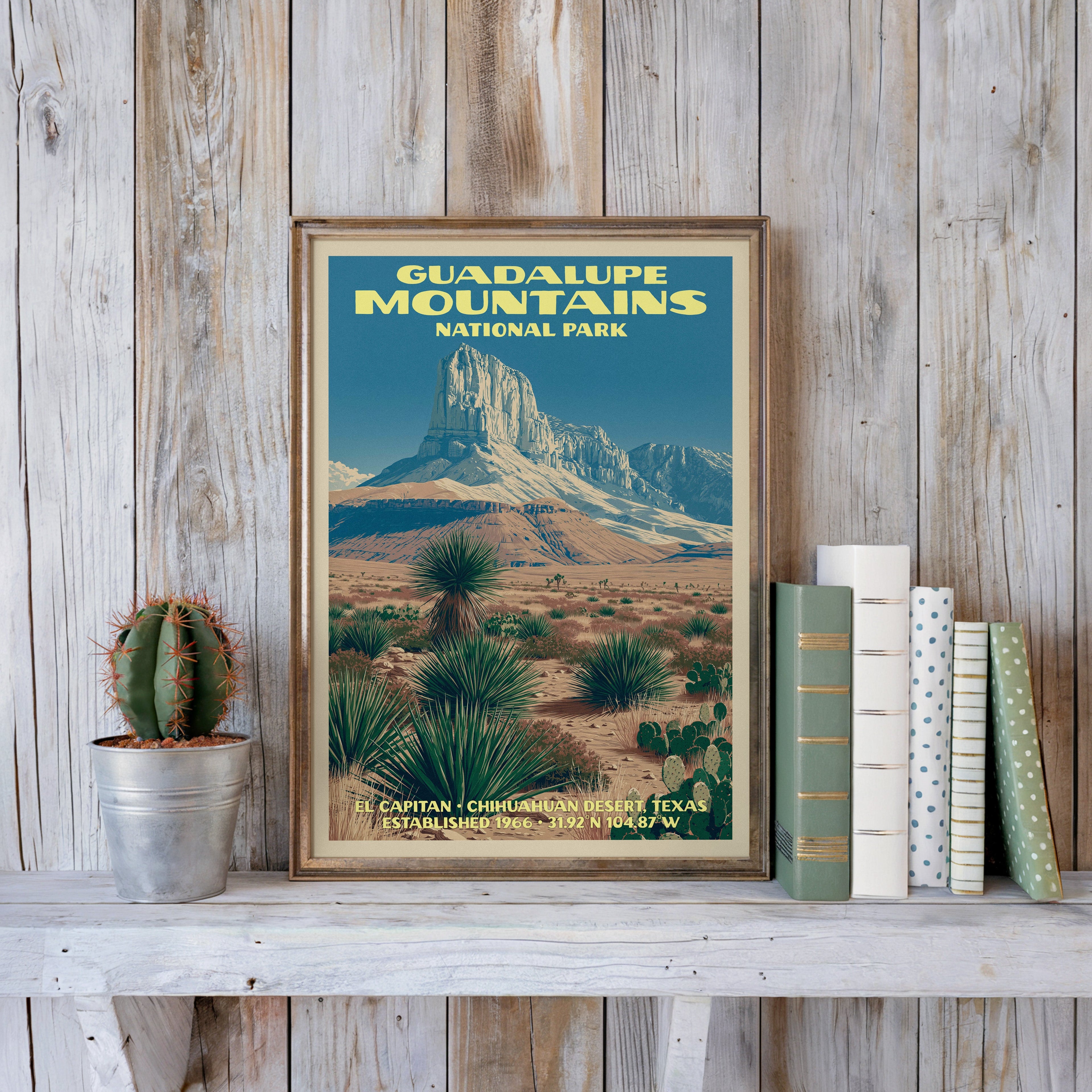 El Capitan poster in a slim gold frame on a whitewashed plank wall beside a tin-potted cactus and pastel books