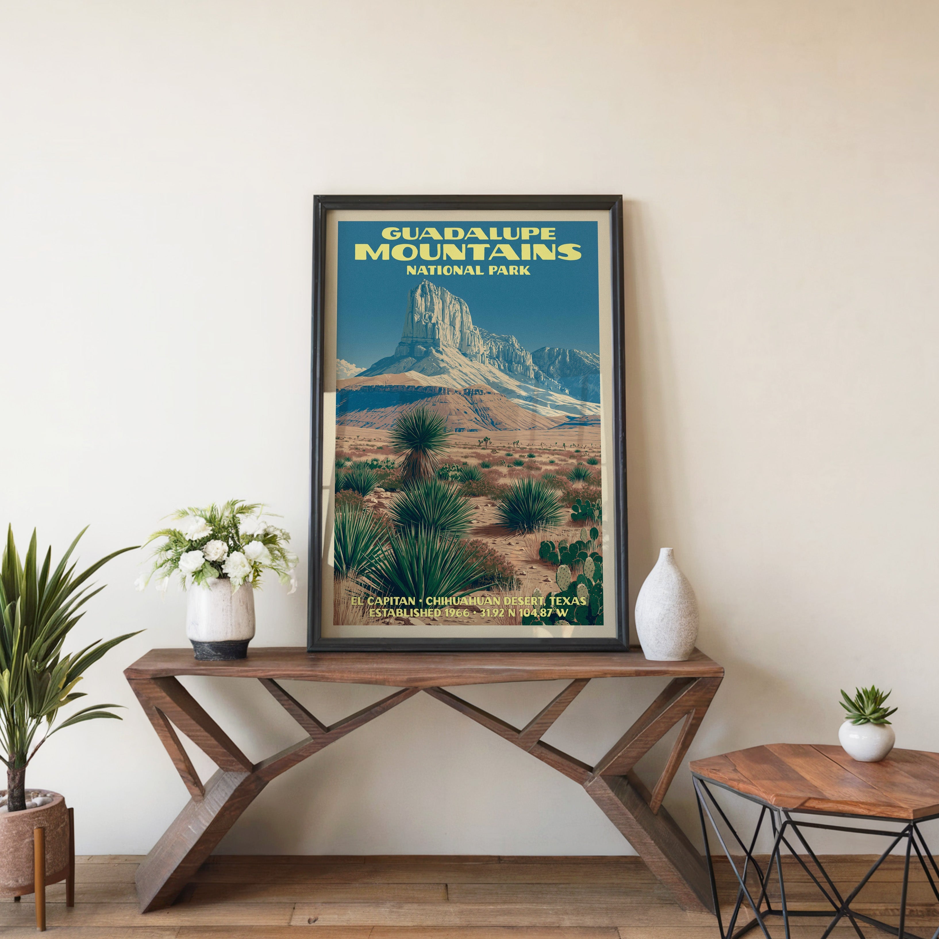 El Capitan desert wall art in a black frame, leaning on a walnut console with white anemones in a stoneware vase