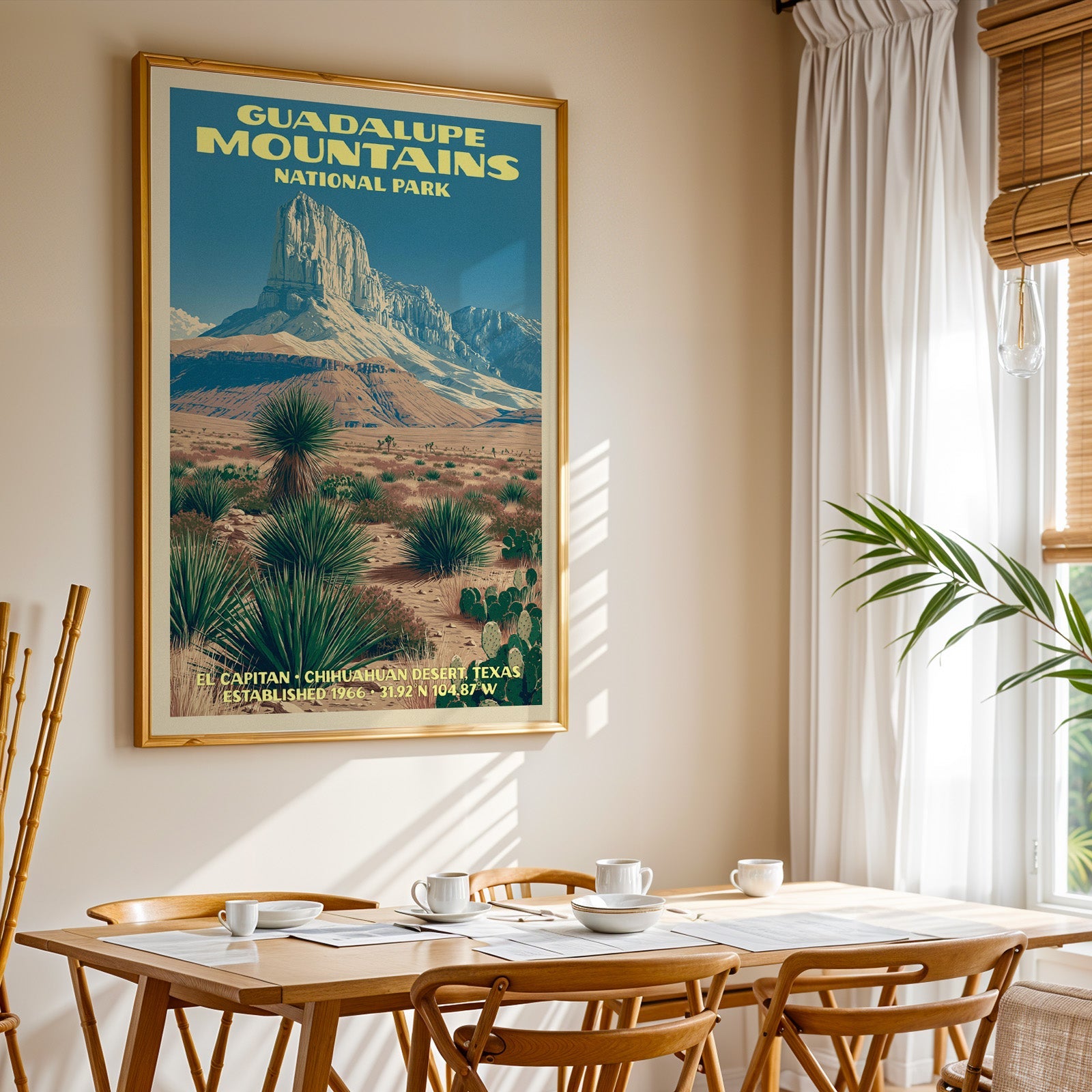 Guadalupe Mountains National Park print in a gold frame above a light oak dining table by a curtained window