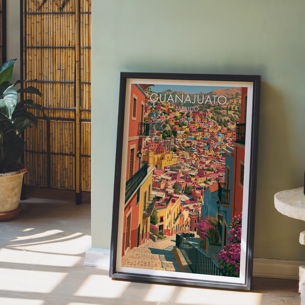 Stacked pink and turquoise rooftops, black frame leaning on pale wood floor by a sage wall and bamboo screen