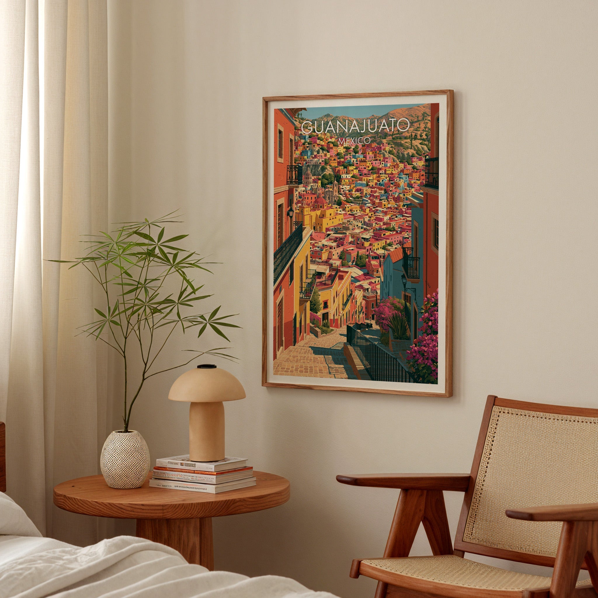 Warm coral cityscape in an oak frame above a round bedside table with a mushroom lamp and bamboo stems