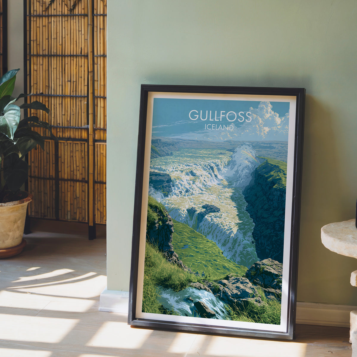 Gullfoss poster, dark frame leaning on a sage-green wall beside a bamboo screen and a peace lily