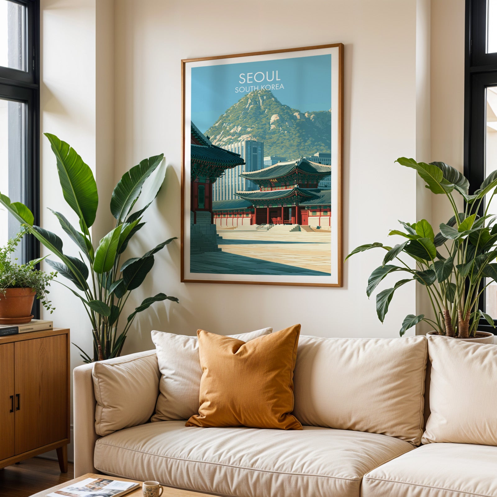 Framed Gyeongbokgung Palace Seoul wall art hanging above a cream sofa in a bright living room with tropical plants