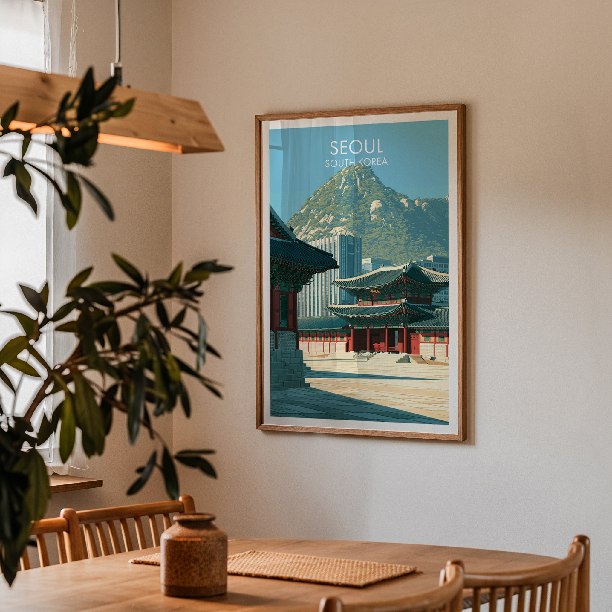 Framed Gyeongbokgung Palace Seoul print on a dining room wall above an oak table in warm afternoon light