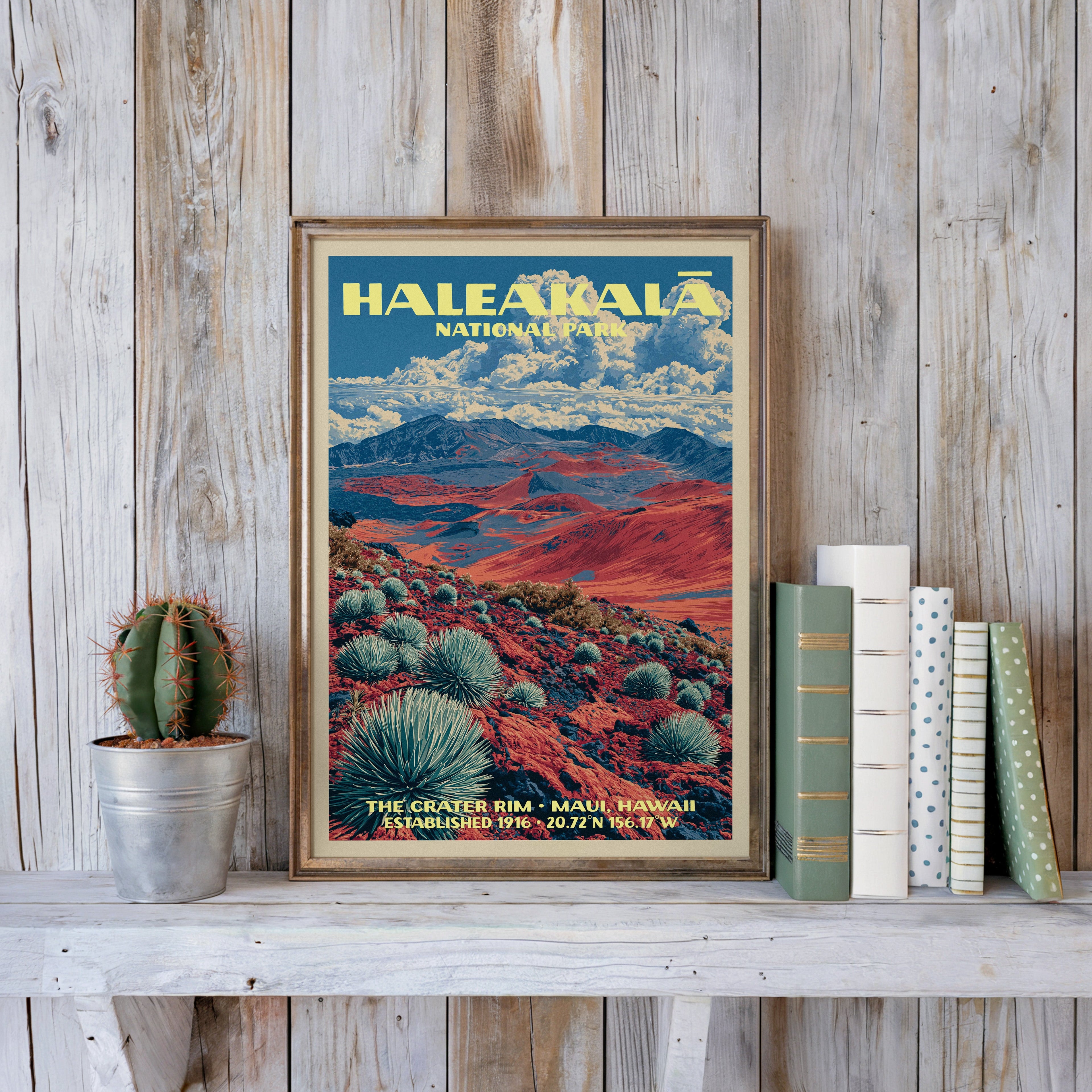 Crater Rim poster in a slim gold frame on a whitewashed plank wall beside a tin-potted cactus and pastel books