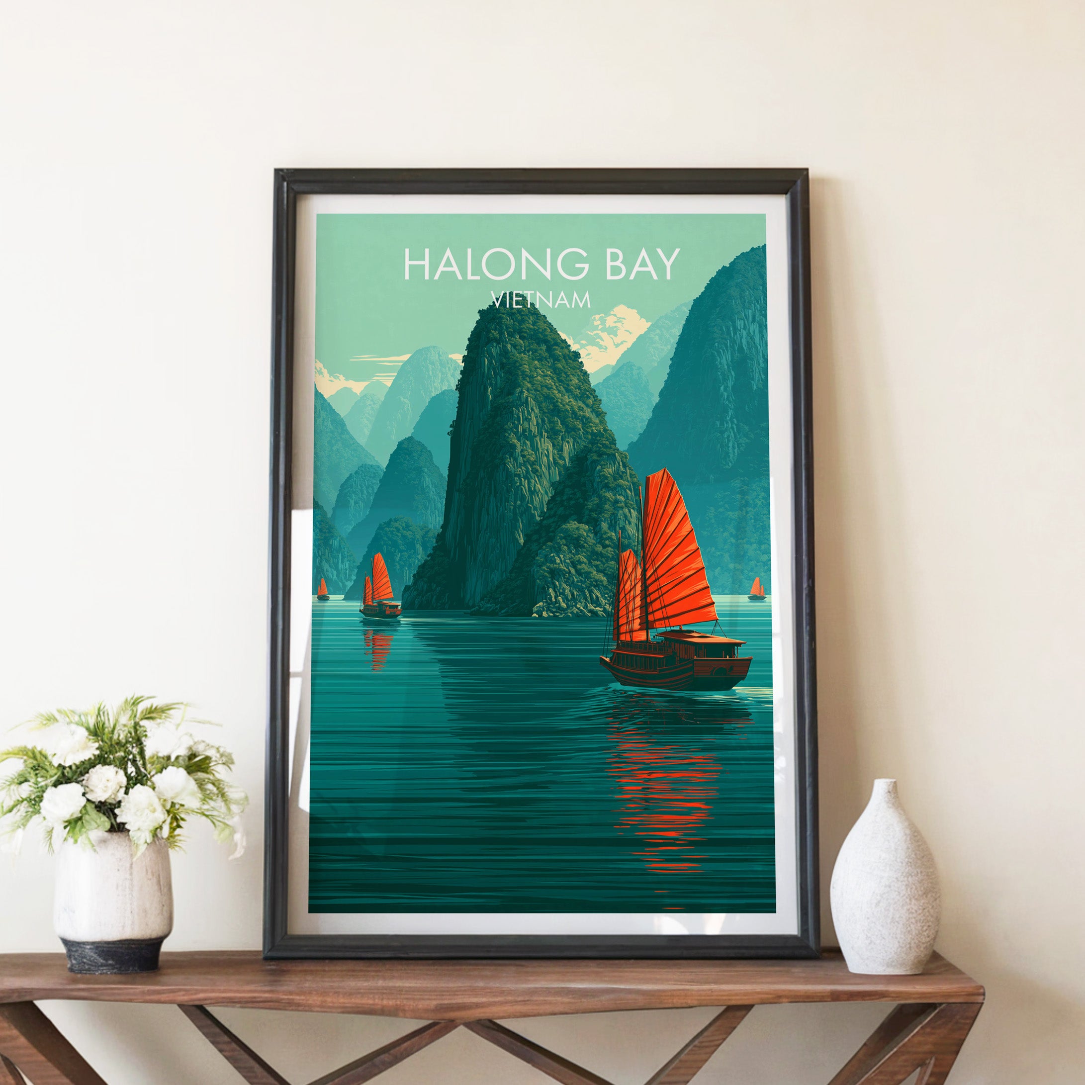 Halong Bay Vietnam travel poster in a black frame on a wooden console table with white flowers