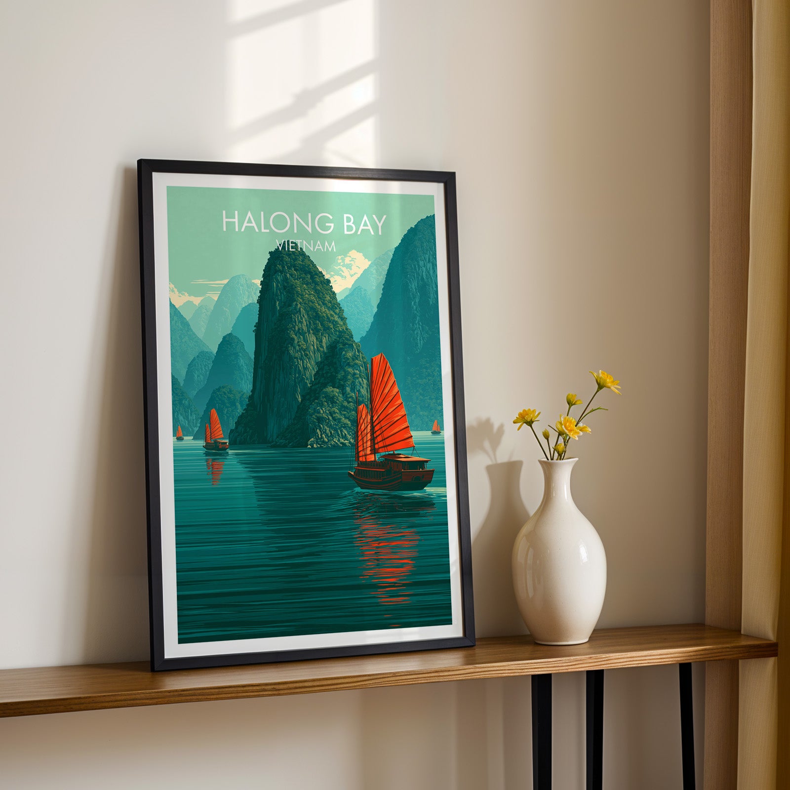 Black framed Halong Bay Vietnam print on a narrow hallway console in sunlight, styled with yellow flowers