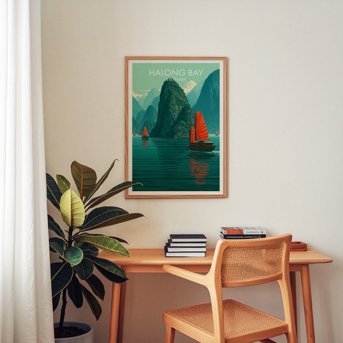 Halong Bay seascape art print in an oak frame above a wooden home office desk with a cane chair and books