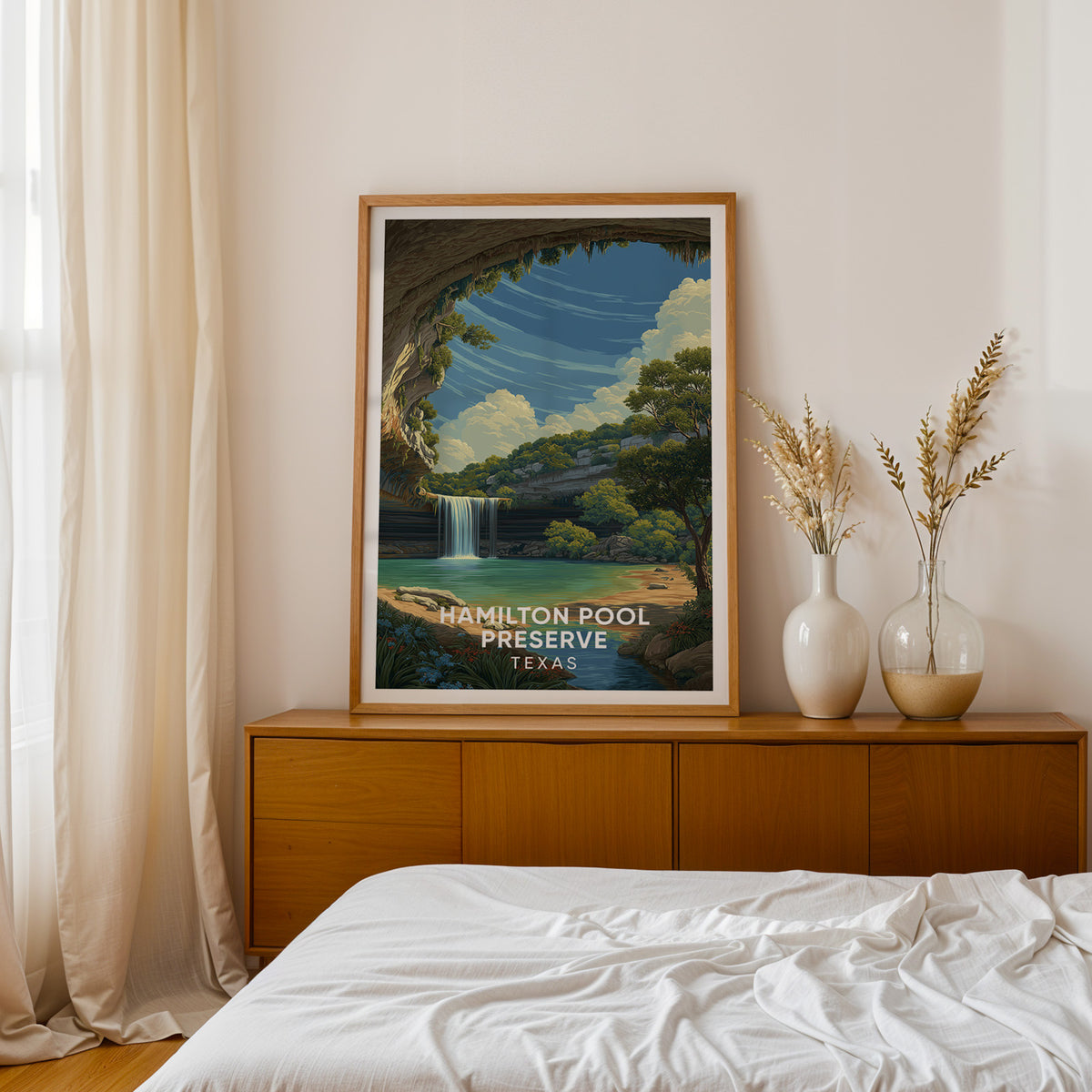Hamilton Pool grotto print framed in oak on a teak sideboard with dried pampas beside the bed