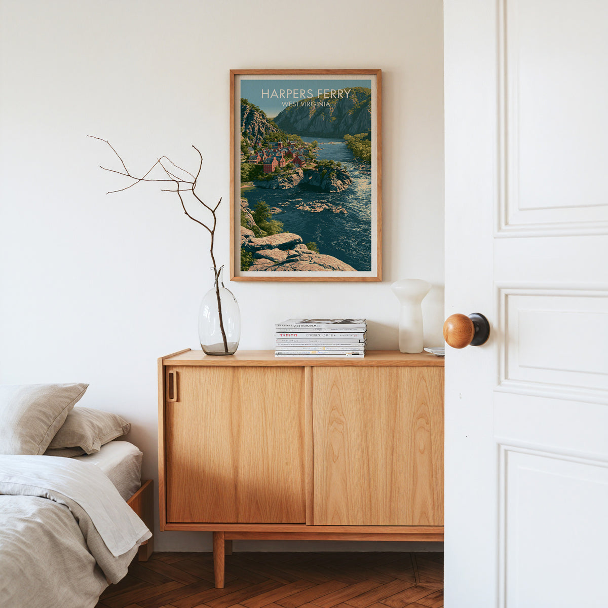 Harpers Ferry wall print in an oak frame on a pale oak sideboard with dried branches, magazines and a white vase