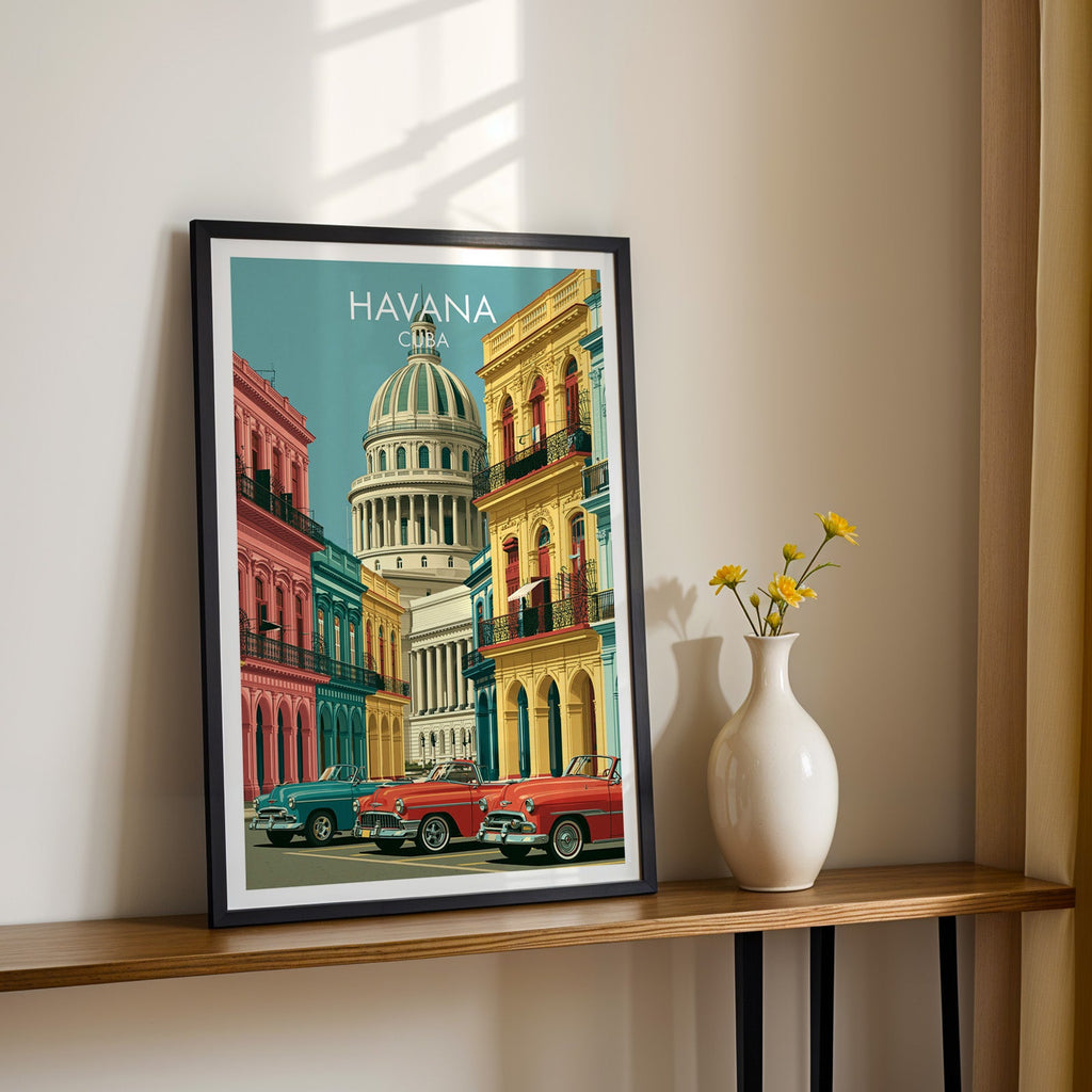 Pink and yellow Havana street art in a black frame on a narrow wood shelf with yellow daisies, sunlit cream wall