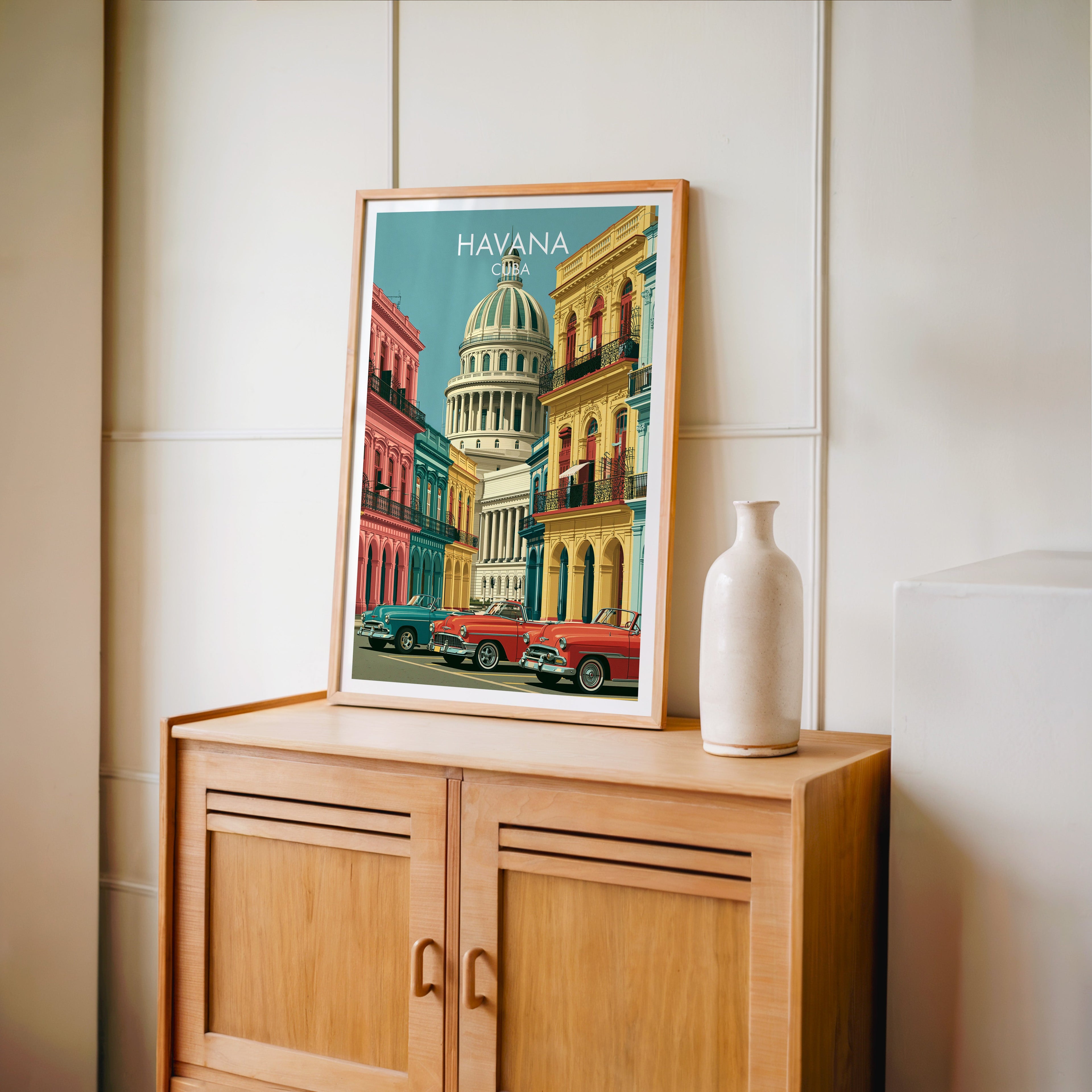 Colonial balconies of Havana in an oak frame on a light oak cabinet, cream panelled wall, tall pale bottle vase