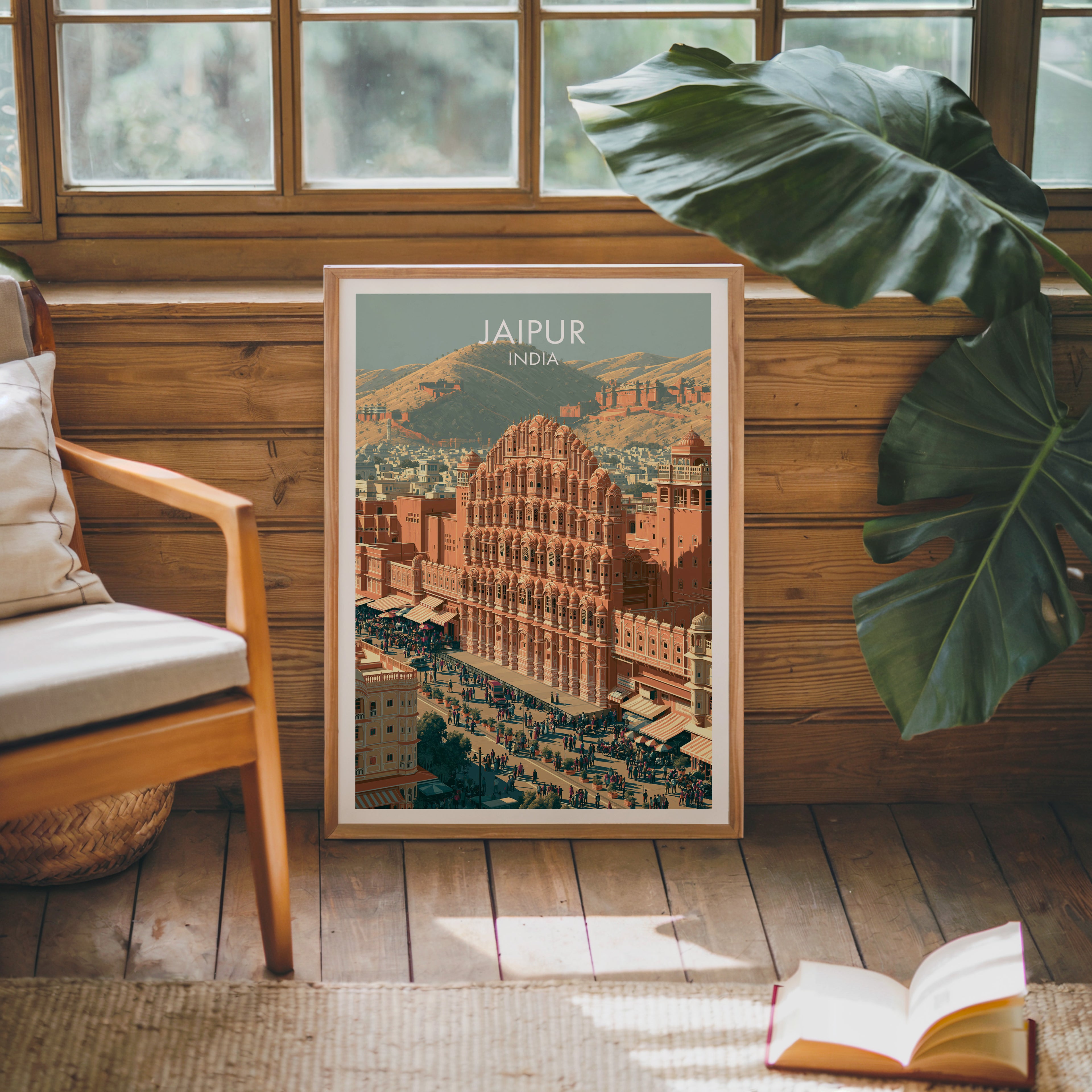 Framed Hawa Mahal Jaipur India poster leaning against a timber cabin wall with monstera leaves and an open book
