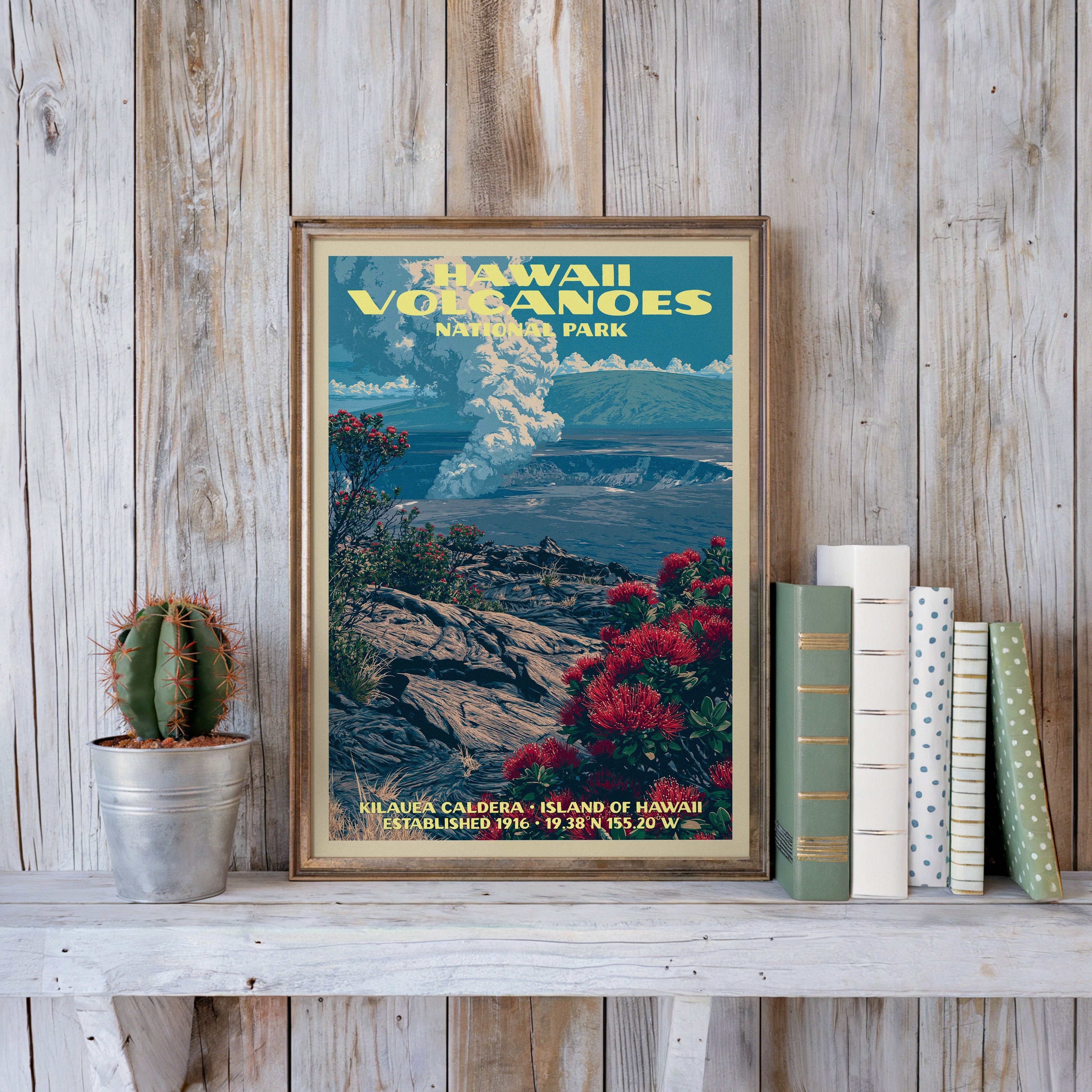 Kilauea Caldera poster in a slim gold frame on a whitewashed plank wall beside a tin-potted cactus and books