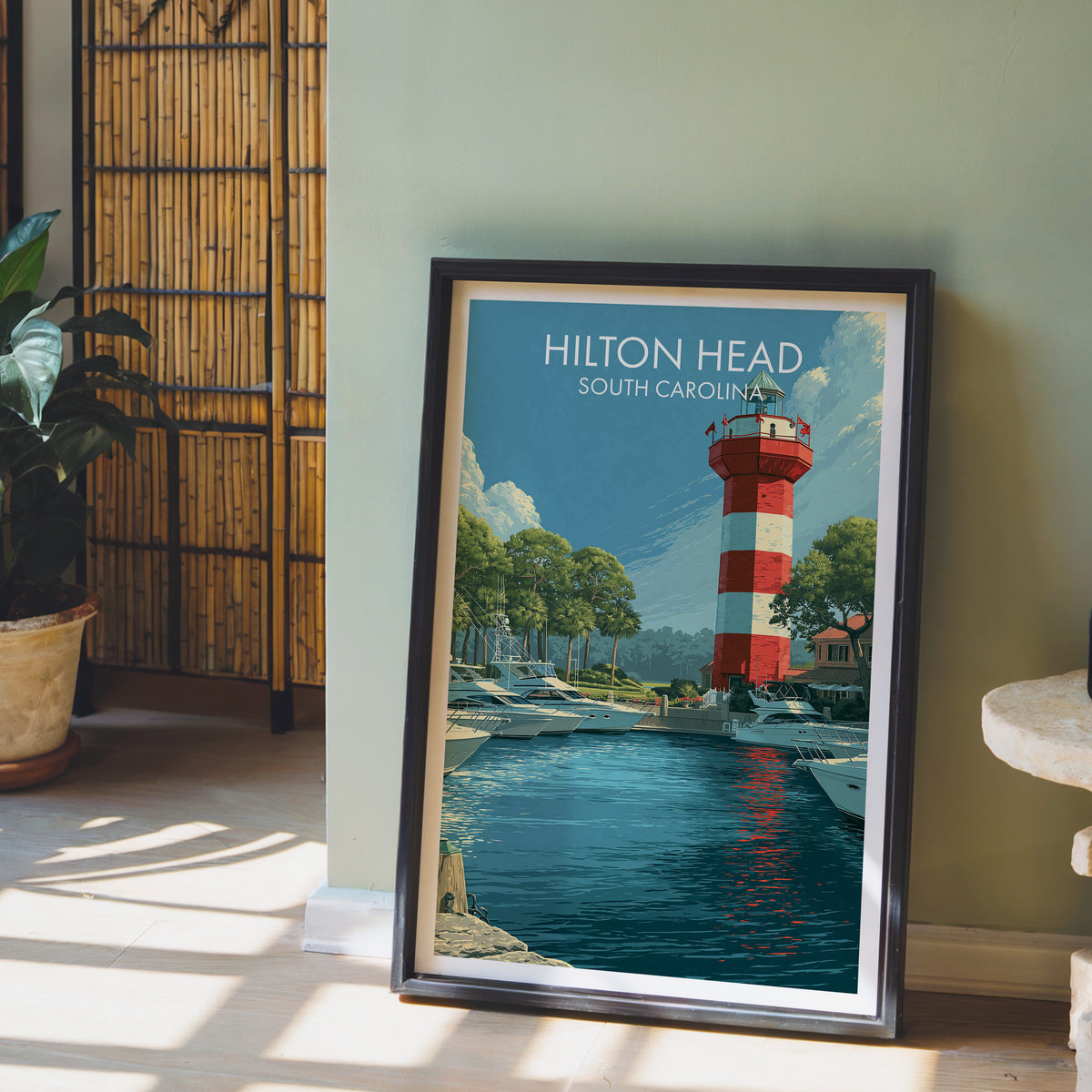 Harbour marina print in a black frame against a sage green wall with a bamboo screen and potted peace lily