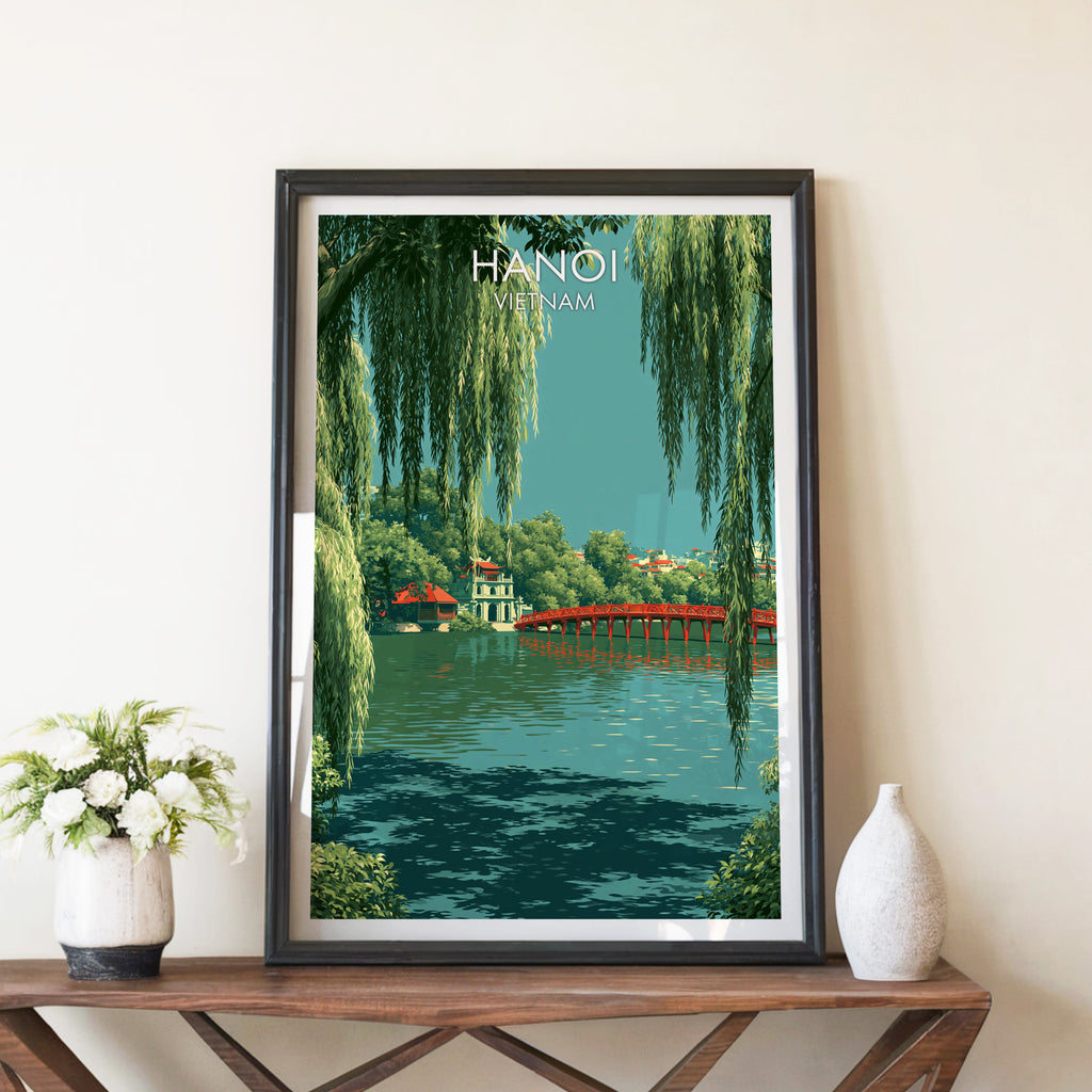 Hoan Kiem Lake Hanoi Vietnam travel poster in a black frame on a wooden console table with white flowers