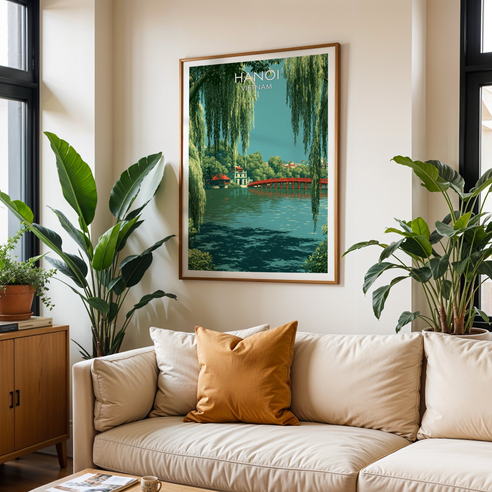 Framed Hoan Kiem Lake Hanoi Vietnam wall art hanging above a cream sofa in a bright living room with tropical plants