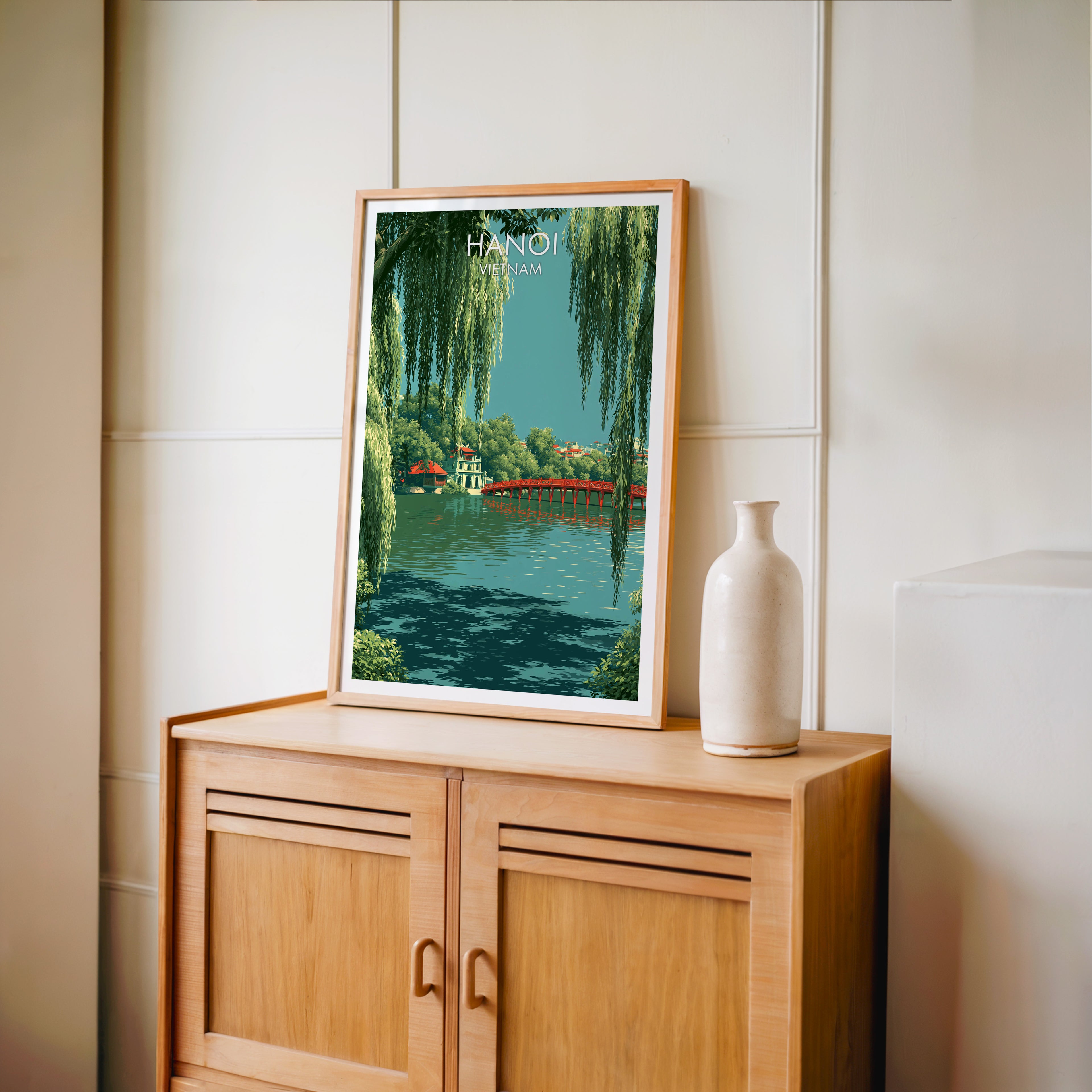 Small Hoan Kiem Lake Hanoi Vietnam travel poster in an oak frame on a mid-century sideboard with a ceramic vase