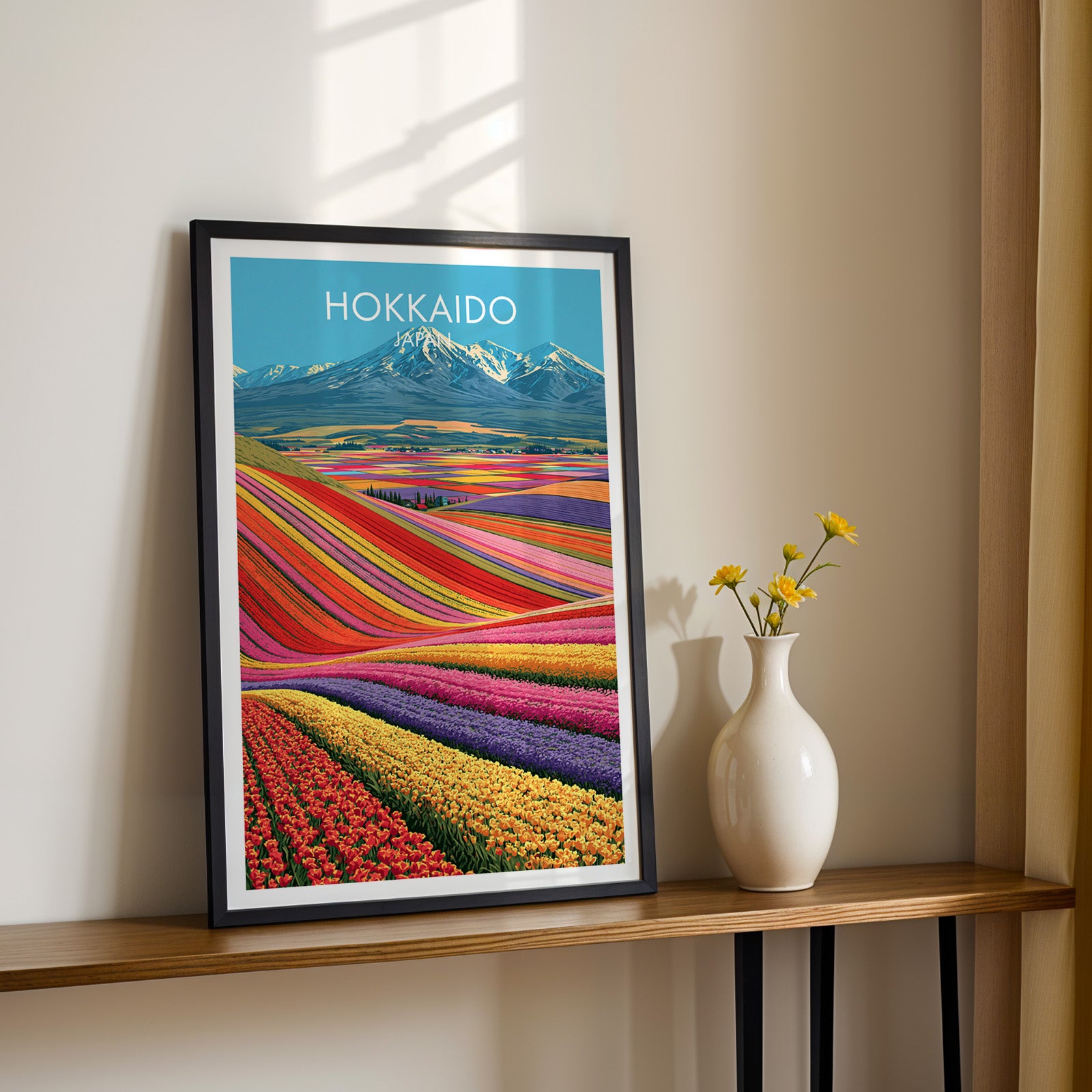 Black framed Hokkaido Japan print on a narrow hallway console in sunlight, styled with yellow flowers