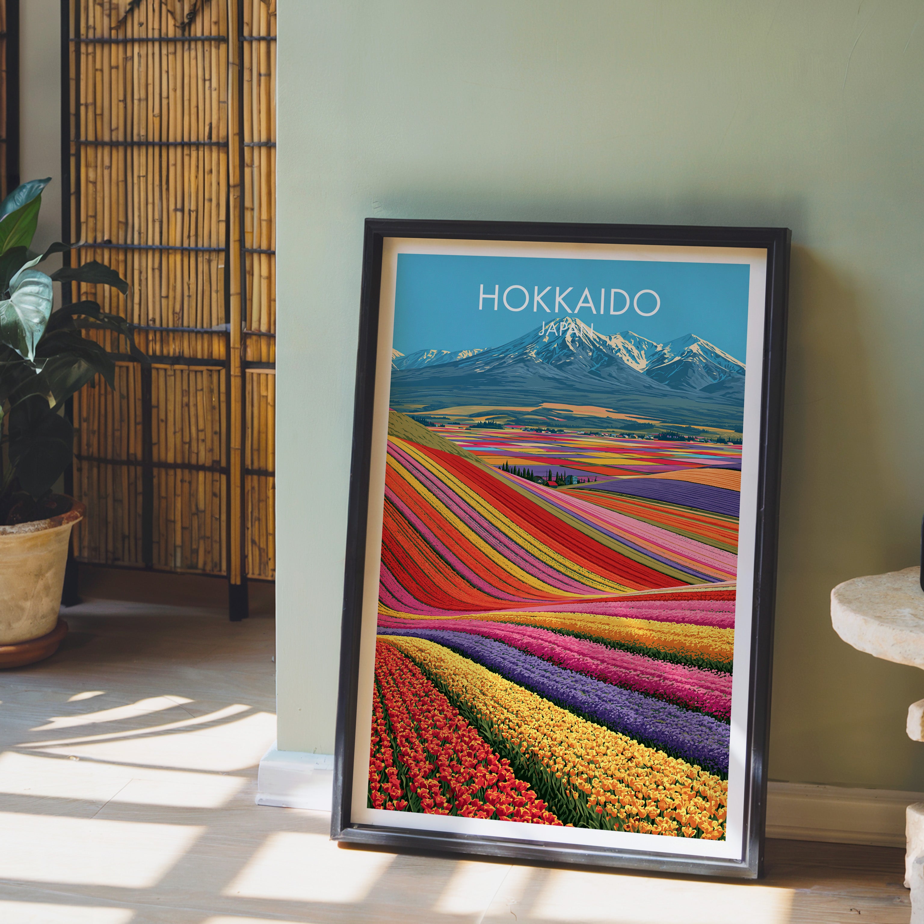 Hokkaido Japan wall art in a black frame leaning against a sage green wall beside a bamboo screen