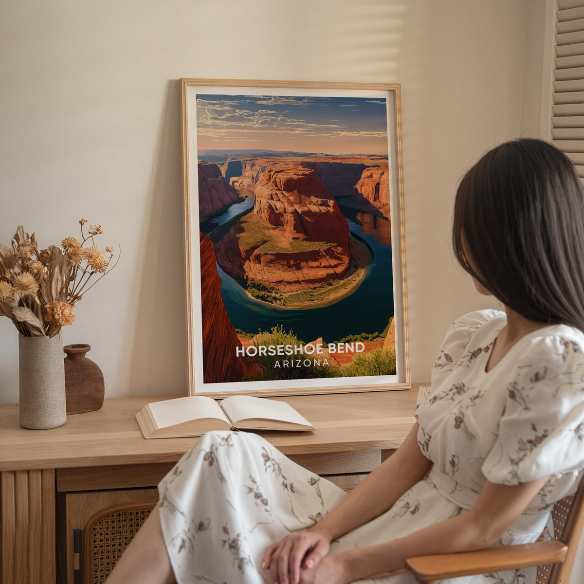 Arizona travel poster on a wood sideboard with dried flowers and a seated woman in a white dress