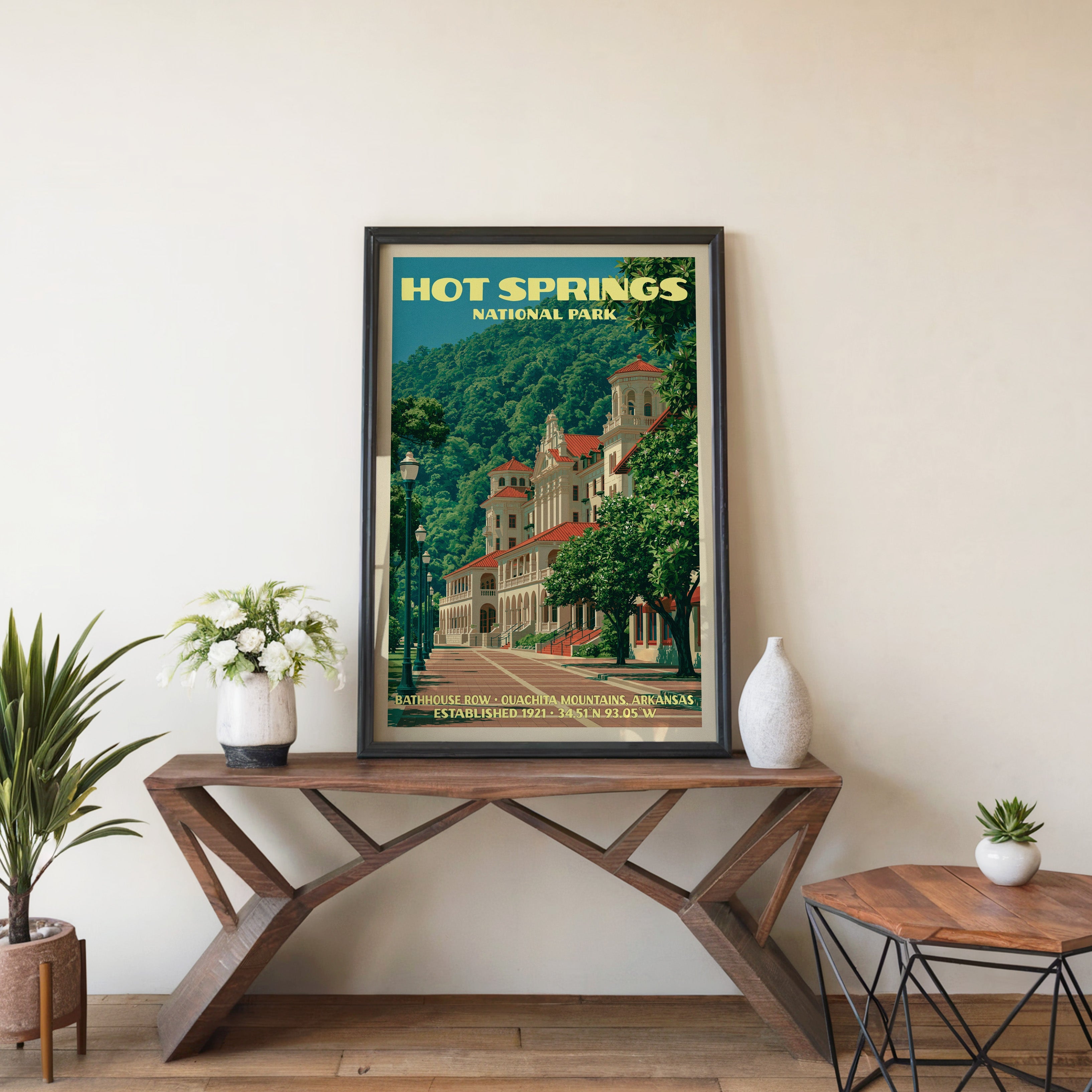 Bathhouse Row wall art in a black frame, leaning on a walnut console with white anemones in a stoneware vase