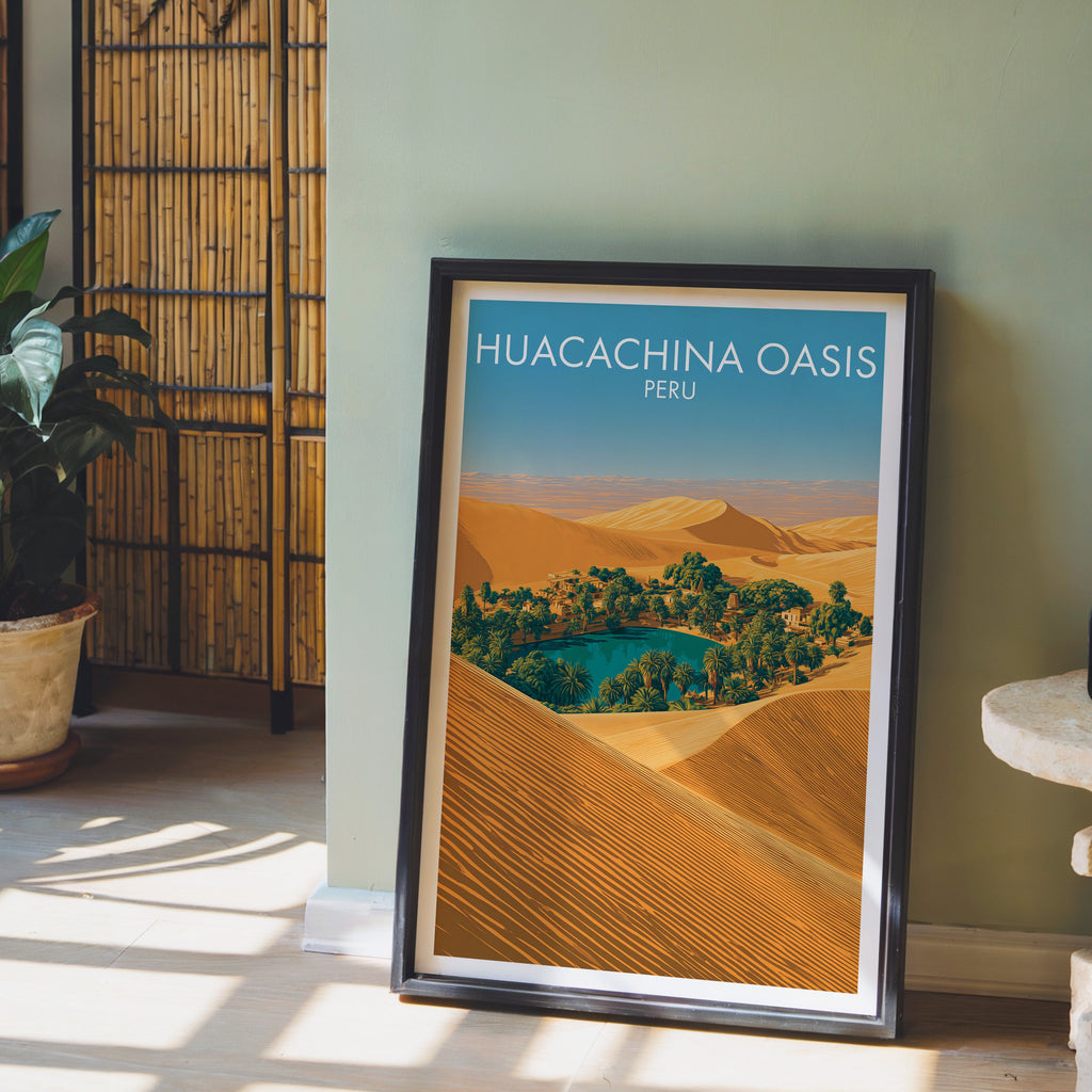 Huacachina lagoon print in a dark brown frame on a sage green wall with a bamboo screen and potted plant