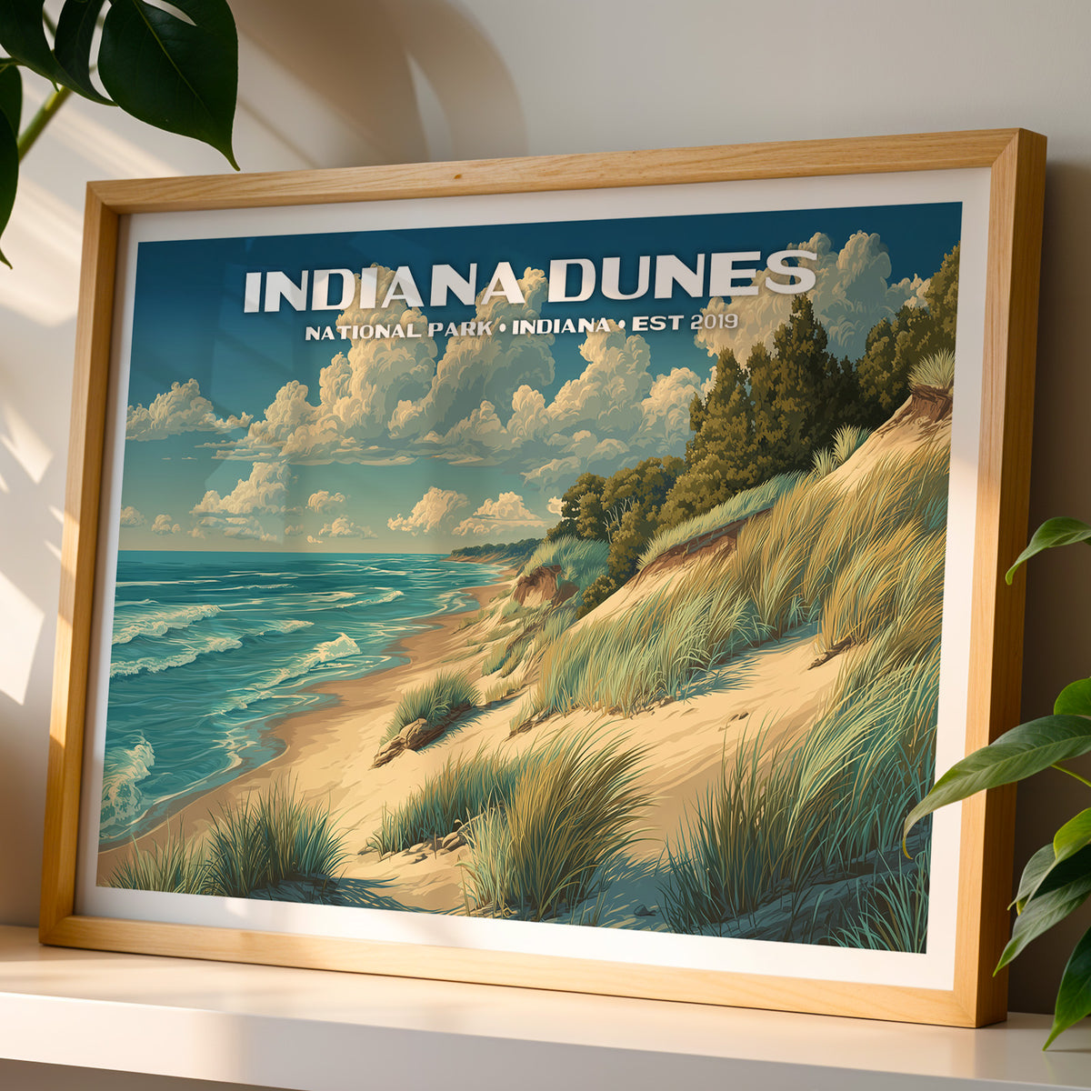 Indiana Dunes National Park wall art print in a light oak frame, leaning on a white shelf in warm sunlight beside a monstera plant
