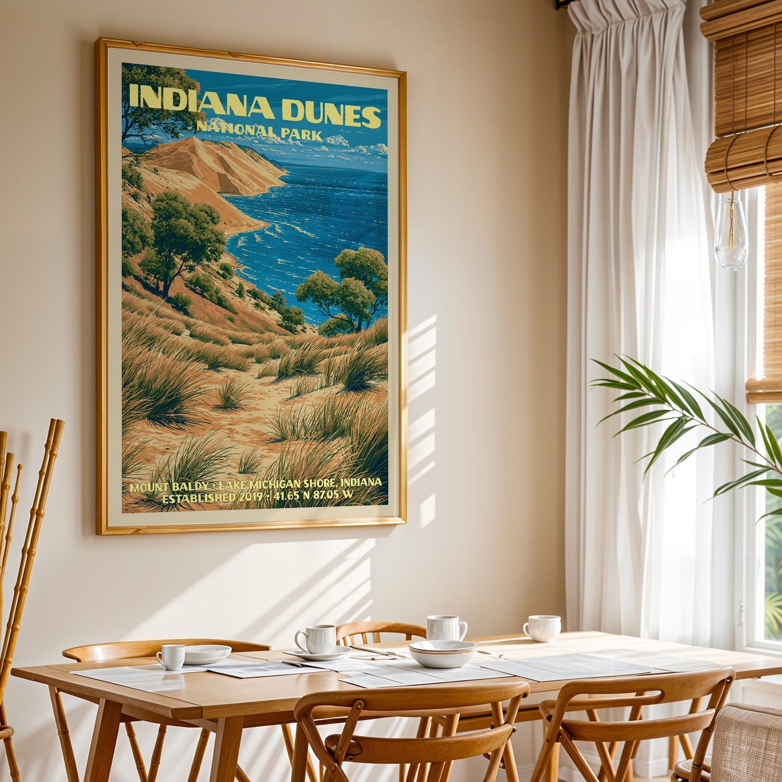 Indiana Dunes National Park print in a gold frame above a light oak dining table by a curtained window