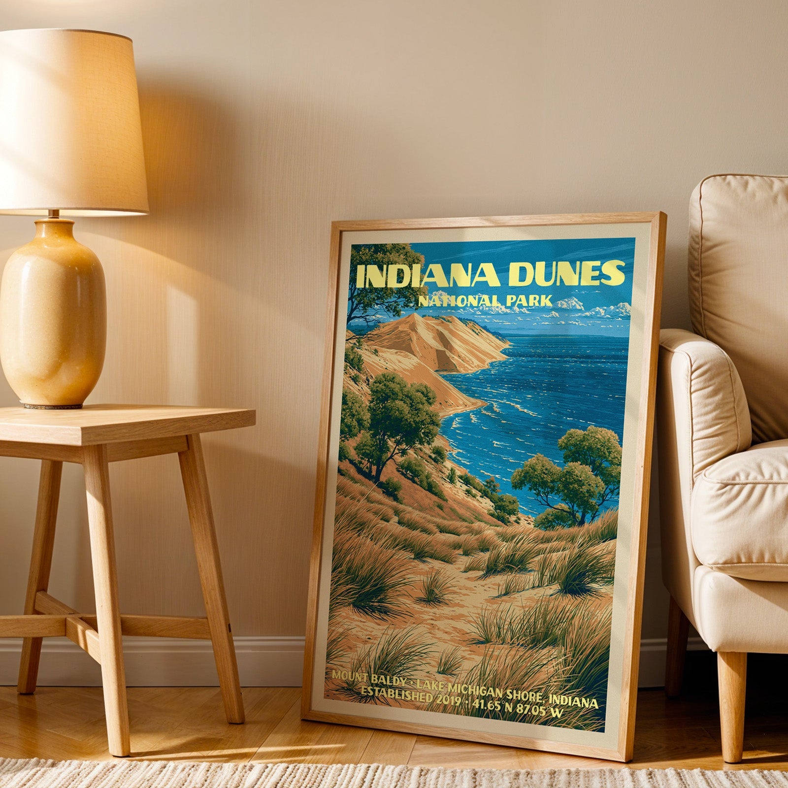 Lake Michigan shore wall art in oak, leaning by a cream armchair and a side table with an ochre lamp