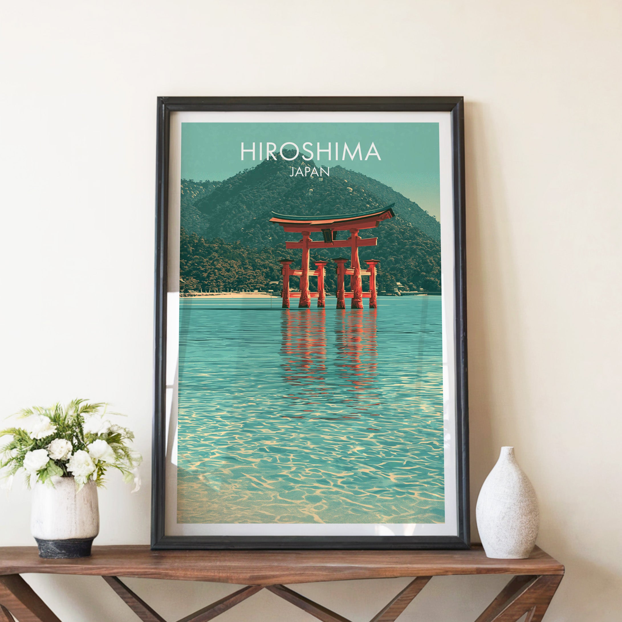 Itsukushima Shrine Miyajima Japan travel poster in a black frame on a wooden console table with white flowers