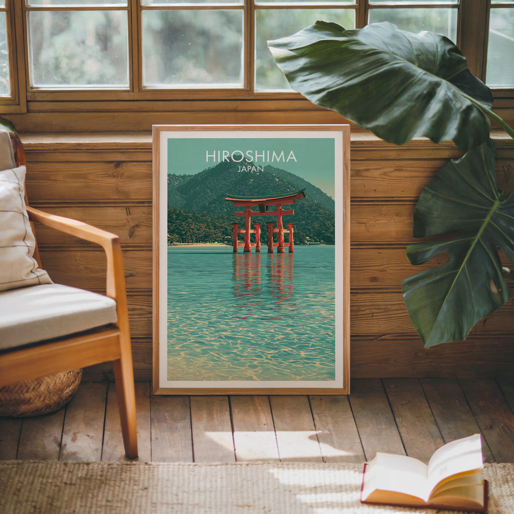 Framed Itsukushima Shrine Miyajima Japan poster leaning against a timber cabin wall with monstera leaves and an open book