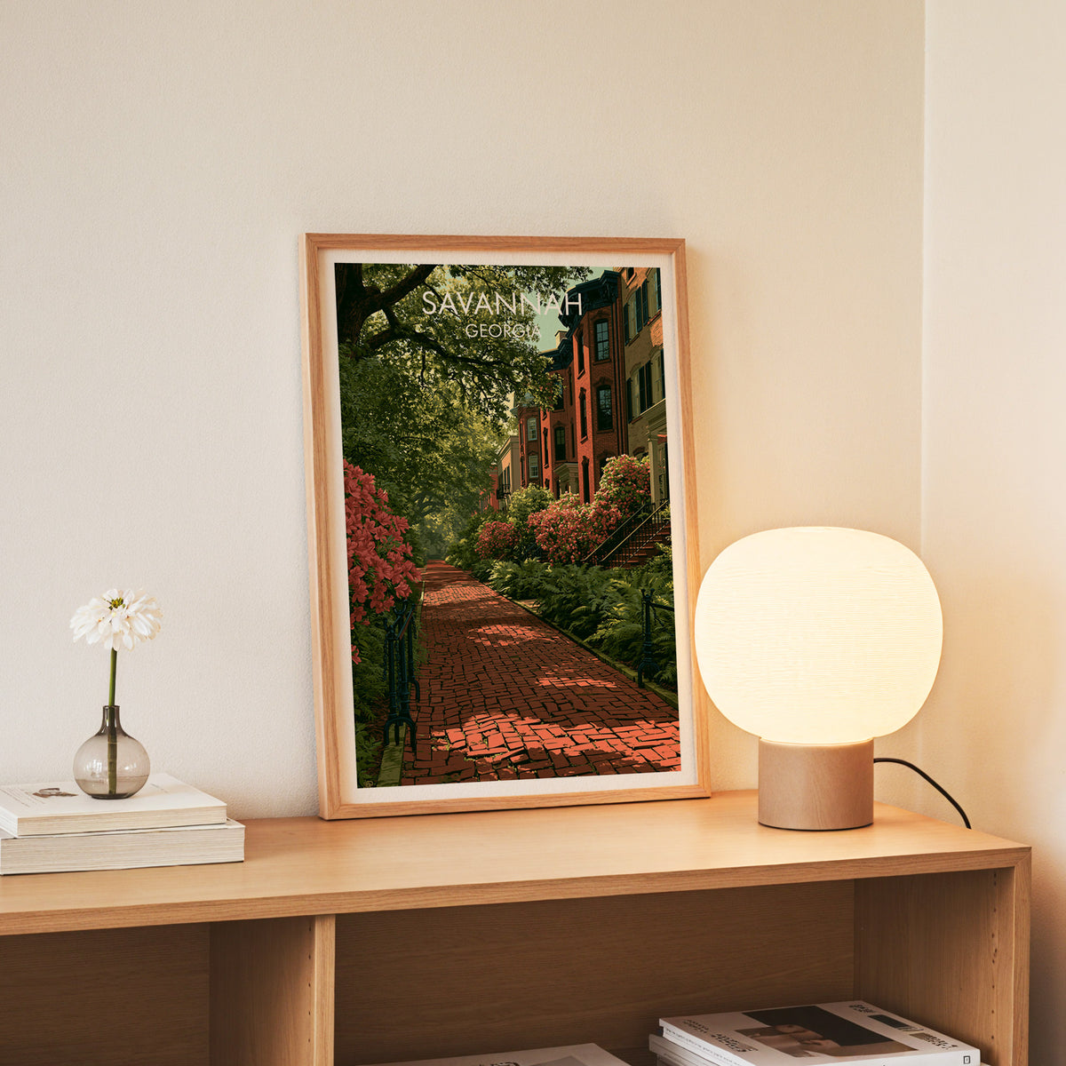 Jones Street canvas print in a slim oak frame on a console beside white daisies in a glass jar
