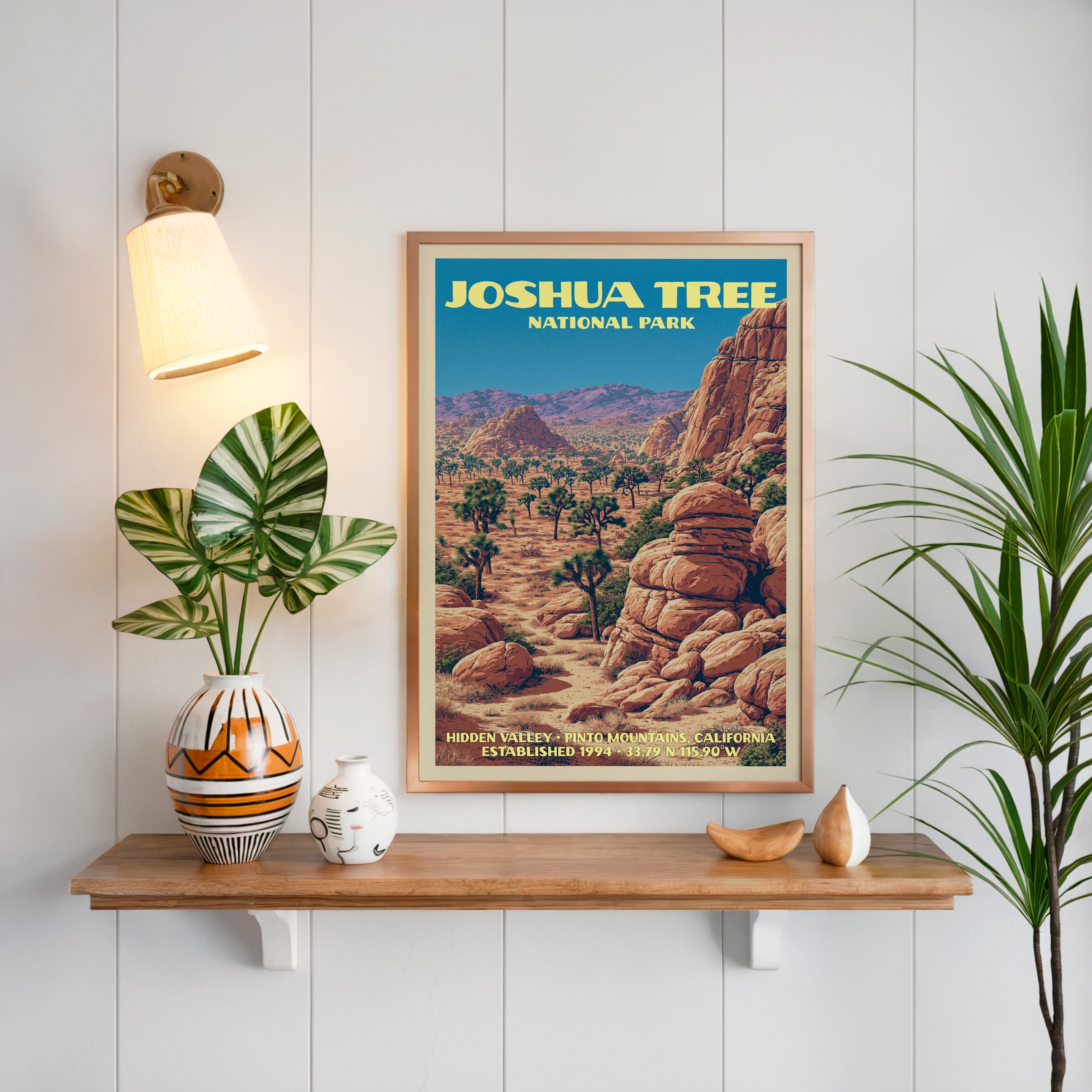 Hidden Valley Joshua Tree print framed on white panelling above an oak shelf with a patterned vase and sconce
