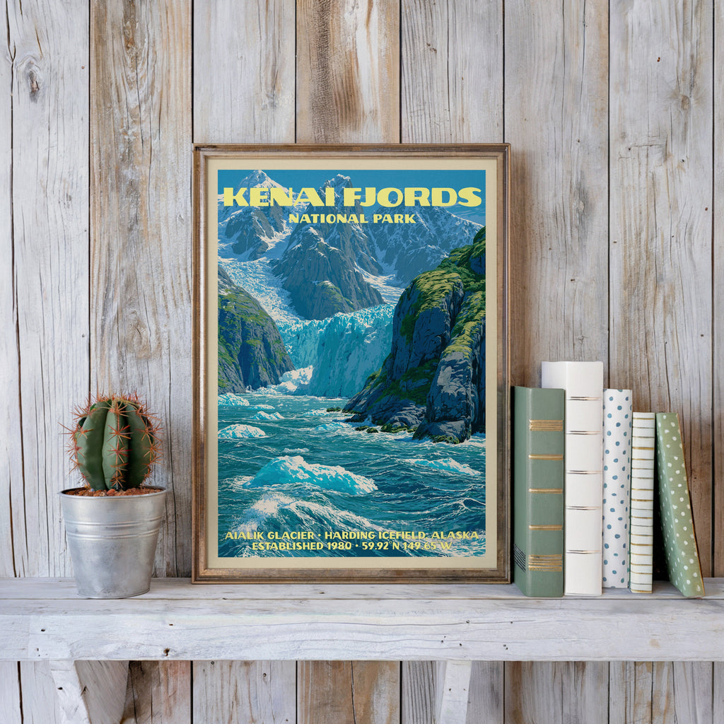 Kenai Fjords vintage poster in a slim gold frame on a whitewashed plank wall beside a cactus and pastel books