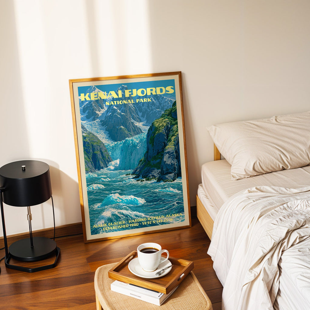 Kenai Fjords Aialik Glacier poster in a gold frame on the floor beside a made bed and a black table lamp