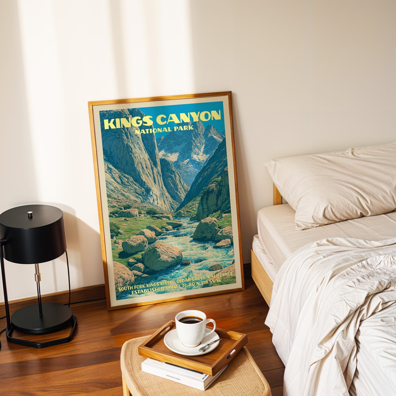 Kings Canyon Cedar Grove poster in a gold frame on the floor beside a made bed and a black table lamp