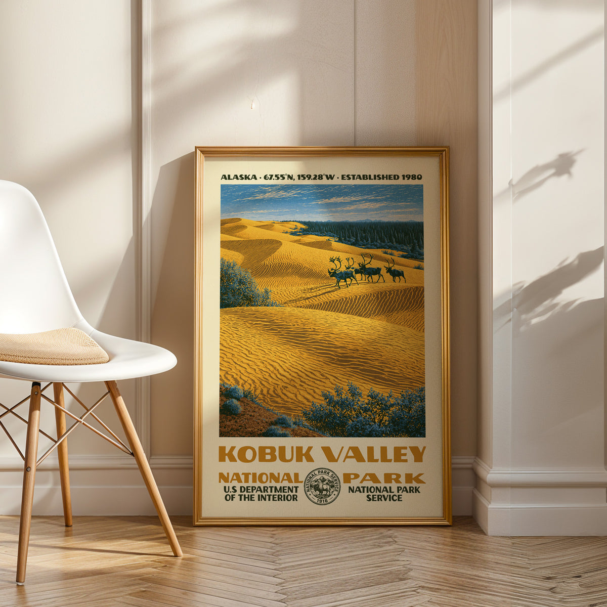 Kobuk Valley National Park vintage WPA art in an oak frame leaning by a white chair on a wood floor