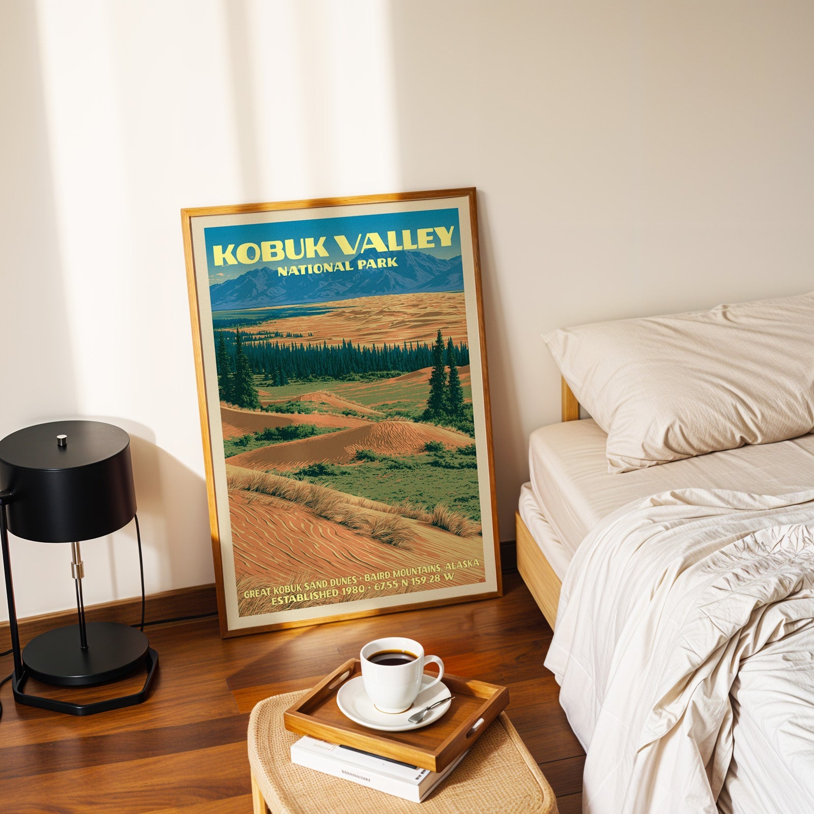 Kobuk Valley dunes poster in a gold frame on the floor beside a made bed and a black table lamp
