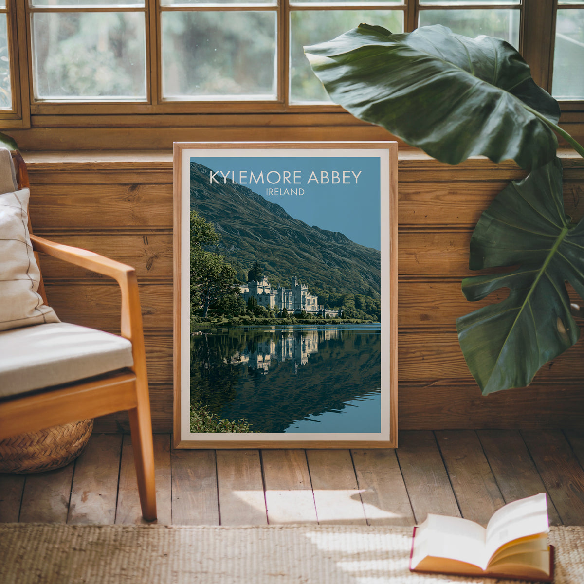 Kylemore Abbey poster, oak frame leaning on a wood-panelled sunroom wall by a mid-century armchair