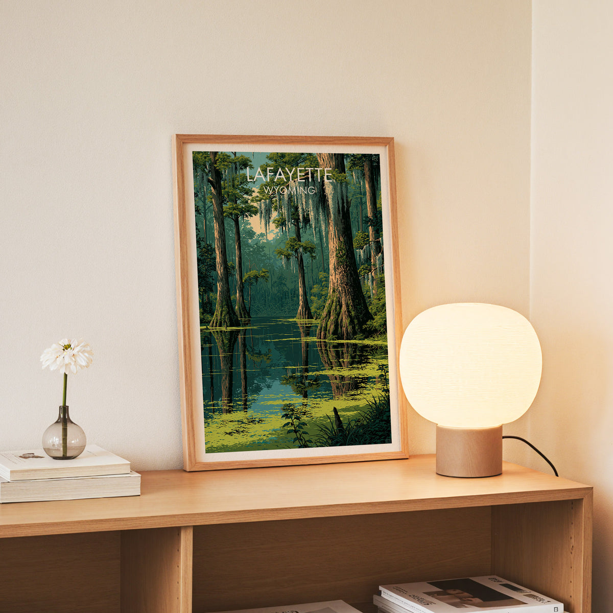 Slim oak framed Lafayette bayou art on an oak console with white daisies in a glass jar and stacked books