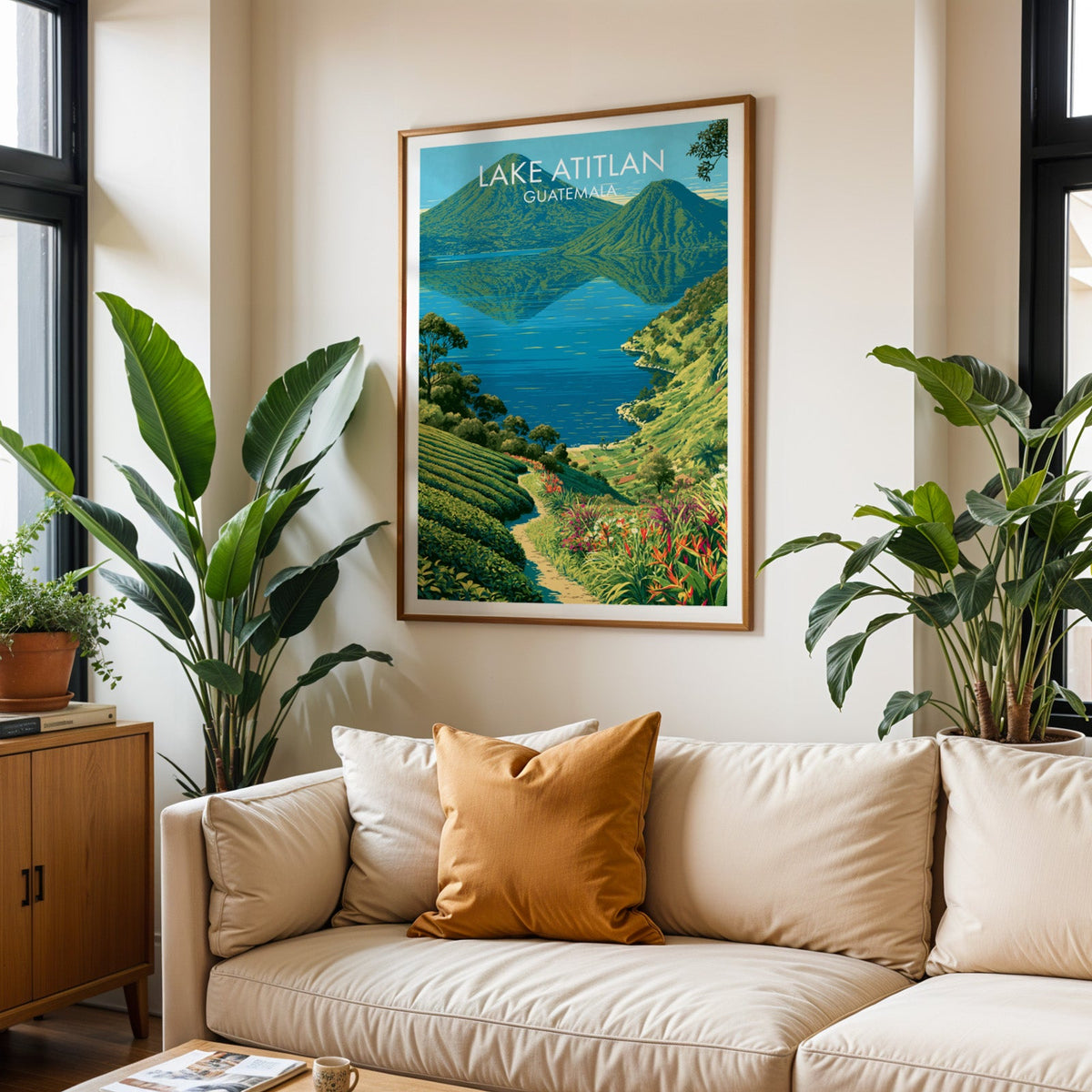 Volcano cones over Lake Atitlan, oak frame above a cream sofa with a burnt-orange cushion and tall tropical plants