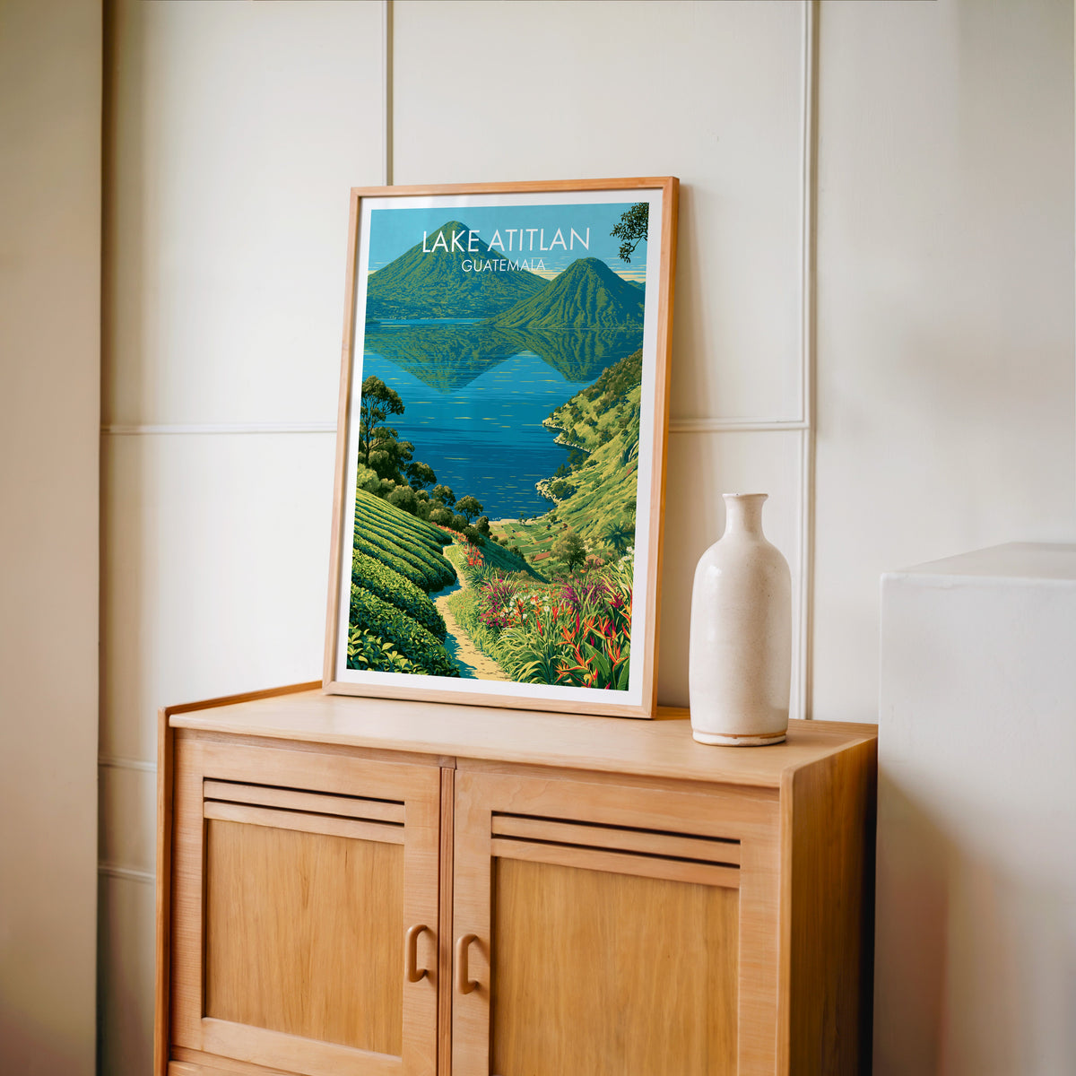 Red heliconia and a winding path in an oak frame on a light oak cabinet, cream panelled wall, pale bottle vase