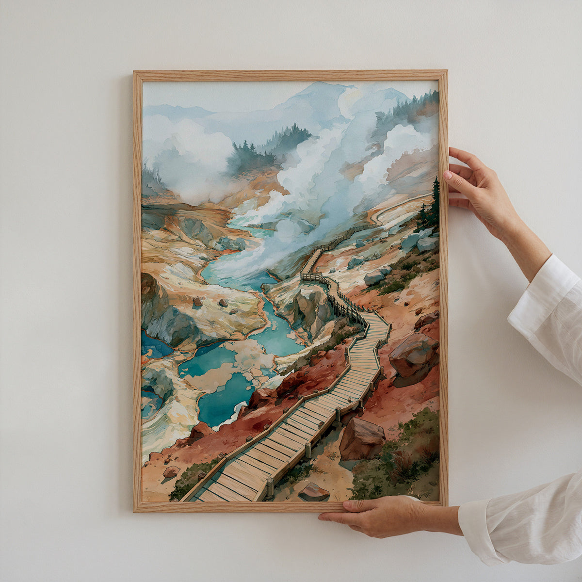 Hands holding an oak-framed Lassen Volcanic National Park watercolor art print against a plain white wall