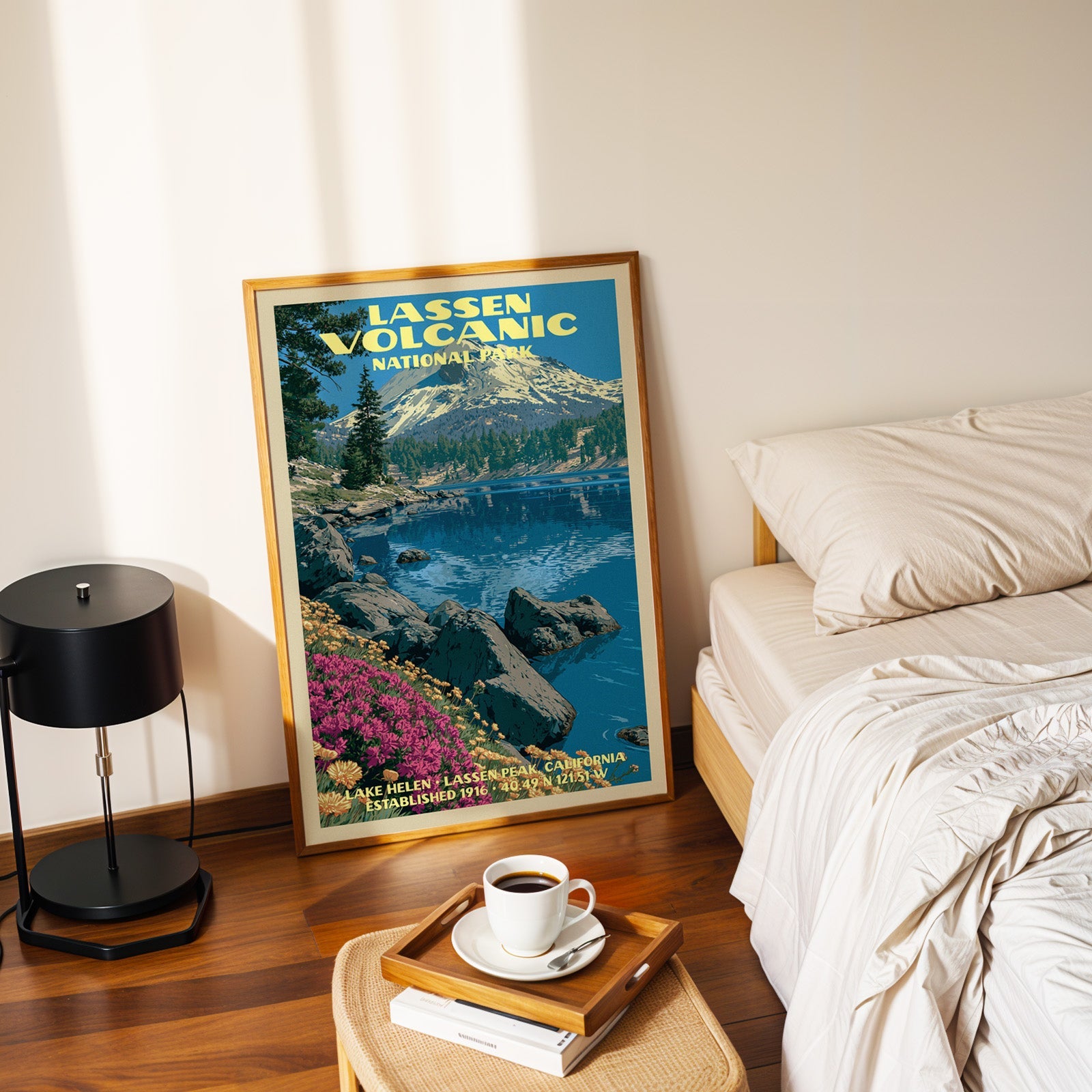 Lassen Volcanic Lake Helen poster in a gold frame on the floor beside a made bed and a black table lamp