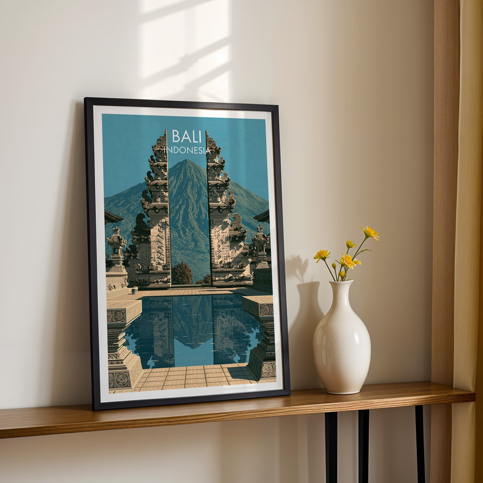 Black framed Lempuyang Temple Bali Indonesia print on a narrow hallway console in sunlight, styled with yellow flowers