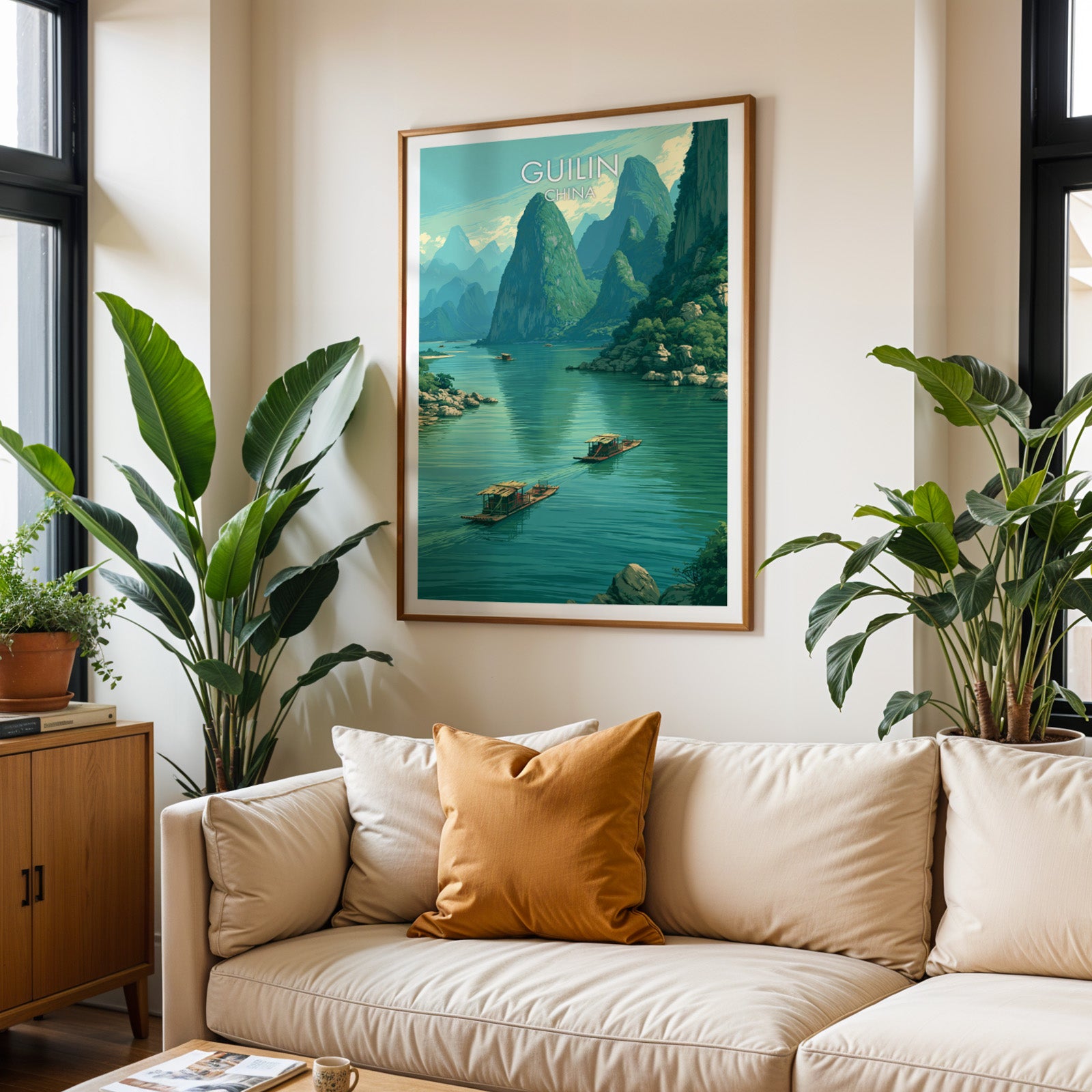 Framed Li River Guilin China wall art hanging above a cream sofa in a bright living room with tropical plants